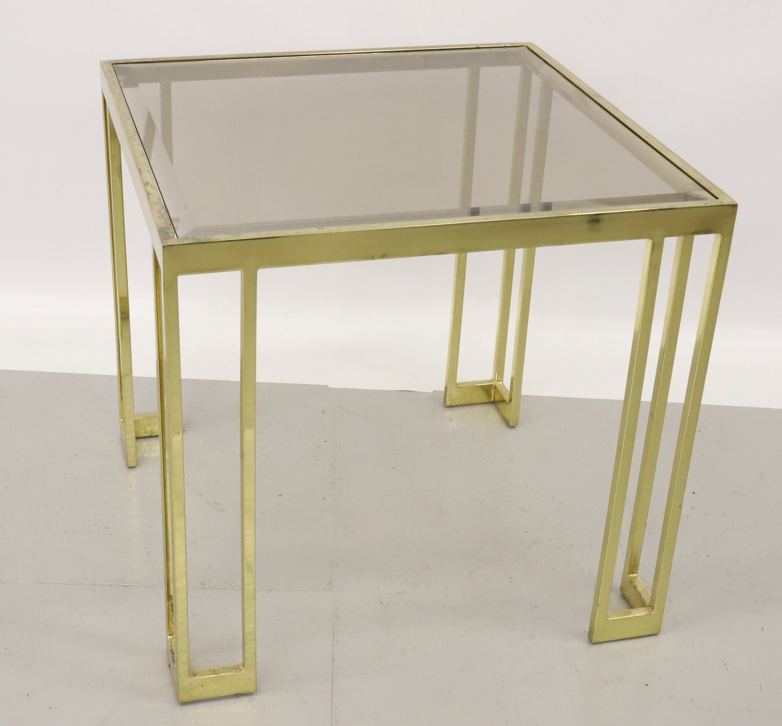 BRASS AND GLASS END TABLE: BRASS BASE WITH SMOKE GLASS BEVELED TOP. 25" X 26" X 26". PLEASE READ CAREFULLY - Terms for Purchasing and Shipping of Auction Items. Please read carefully before bidding. All payments for purchases w