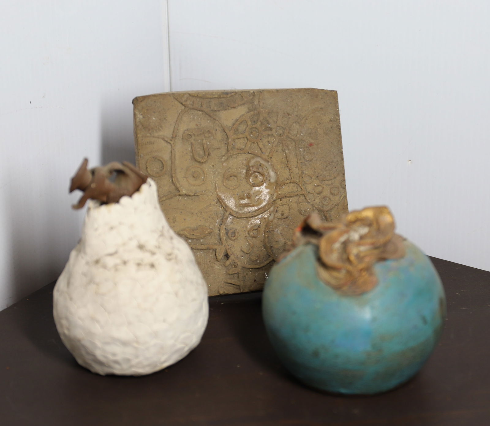 LOT OF STUDIO POTTERY: POTTERY TILE WITH FACES 6 1/4" X 6 1/4", WHITE "VASE" 6" H. AND BLUE VASE (SGND. ON BOTTOM). PLEASE READ CAREFULLY – THIS IS AN ONLINE ONLY AND ONSITE AUCTION. THE ADDRESS WILL BE GIVEN AFTER THE AU