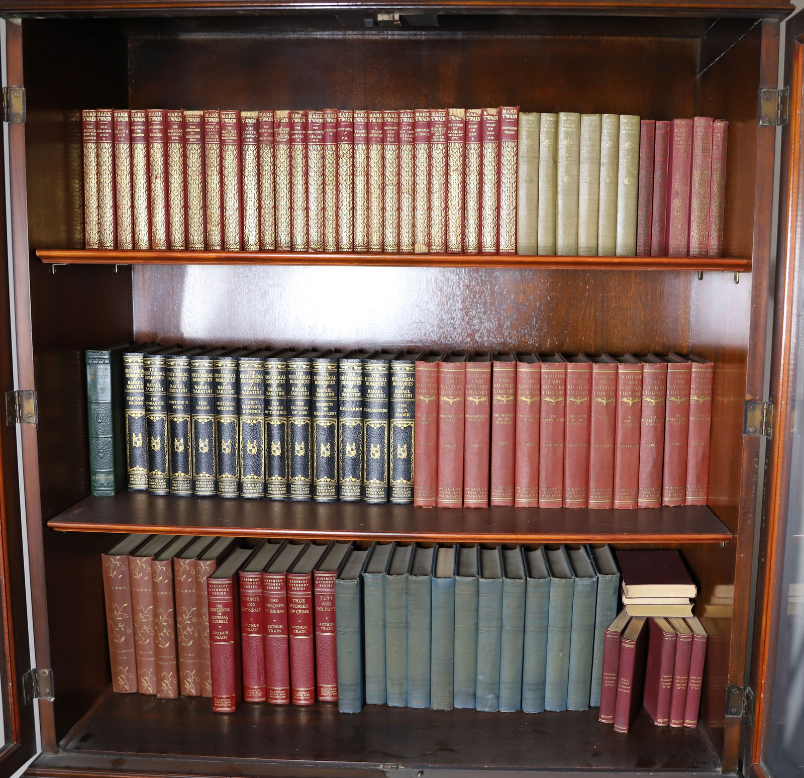 THREE SHELVES OF BOOKS: MARK TWAIN HARPER & BROTHERS NY LIMP LEATHER BOUND VOLUME SET LARGE, PHILLIP OPPENHEIM SET LITTLE BROWN & CO 1925, RAPHAEL SABATINI MCKINLEY, STONE , HC BAILEY MCKINLEY STONE, PLUS AUTHORS E.A. POE, A