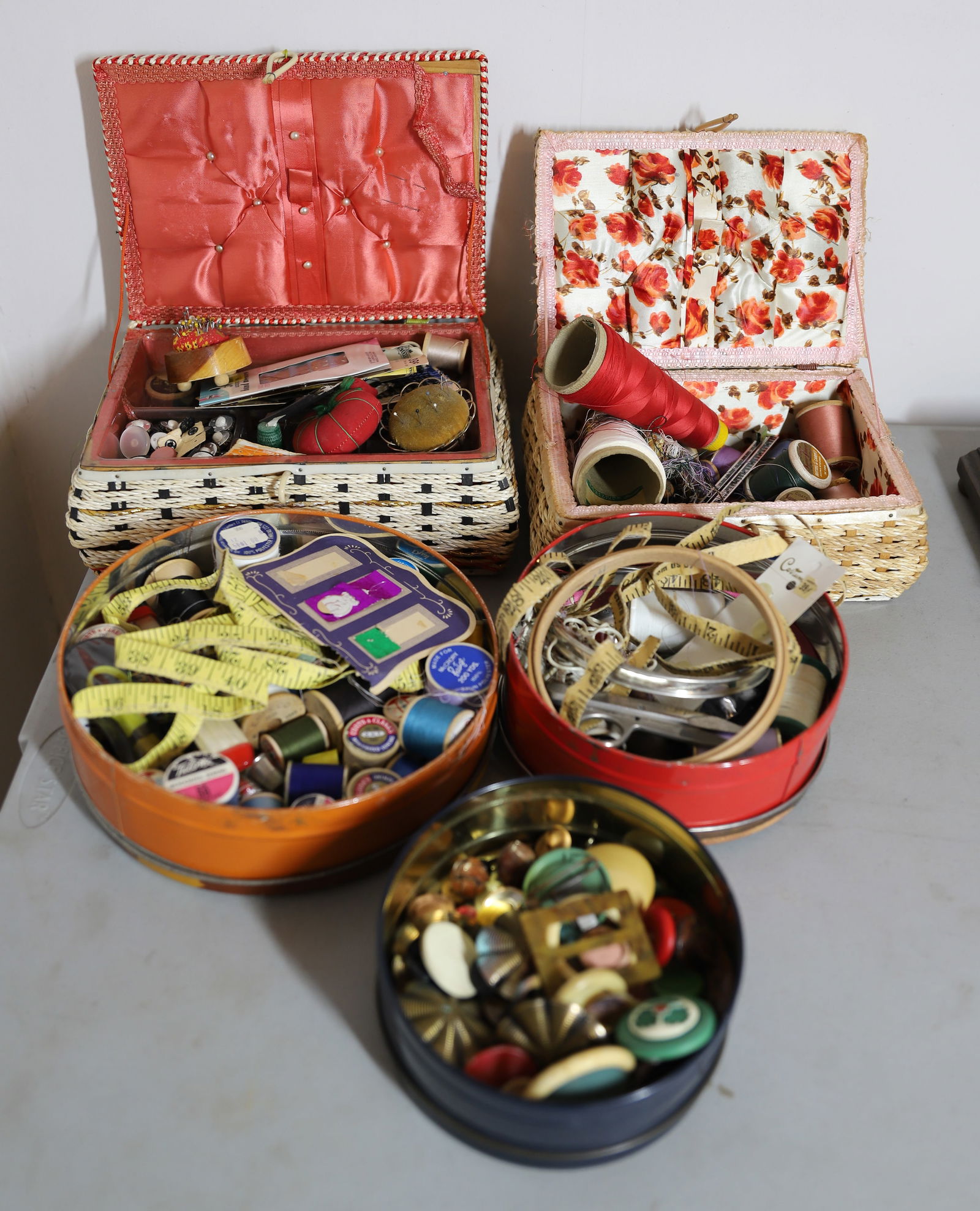 SEWING GROUPING: INCLUDES, TWO SEWING BASKETS, TIN OF VINTAGE BUTTONS, TWO TINS OF THREAD IMPLEMENTS, TOMATO PIN CUSHION,PIN CUSHIONS, THIMBLES, NEEDLES, SCISSORS ETC 17" X 19" PLEASE READ CAREFULLY – THIS IS AN