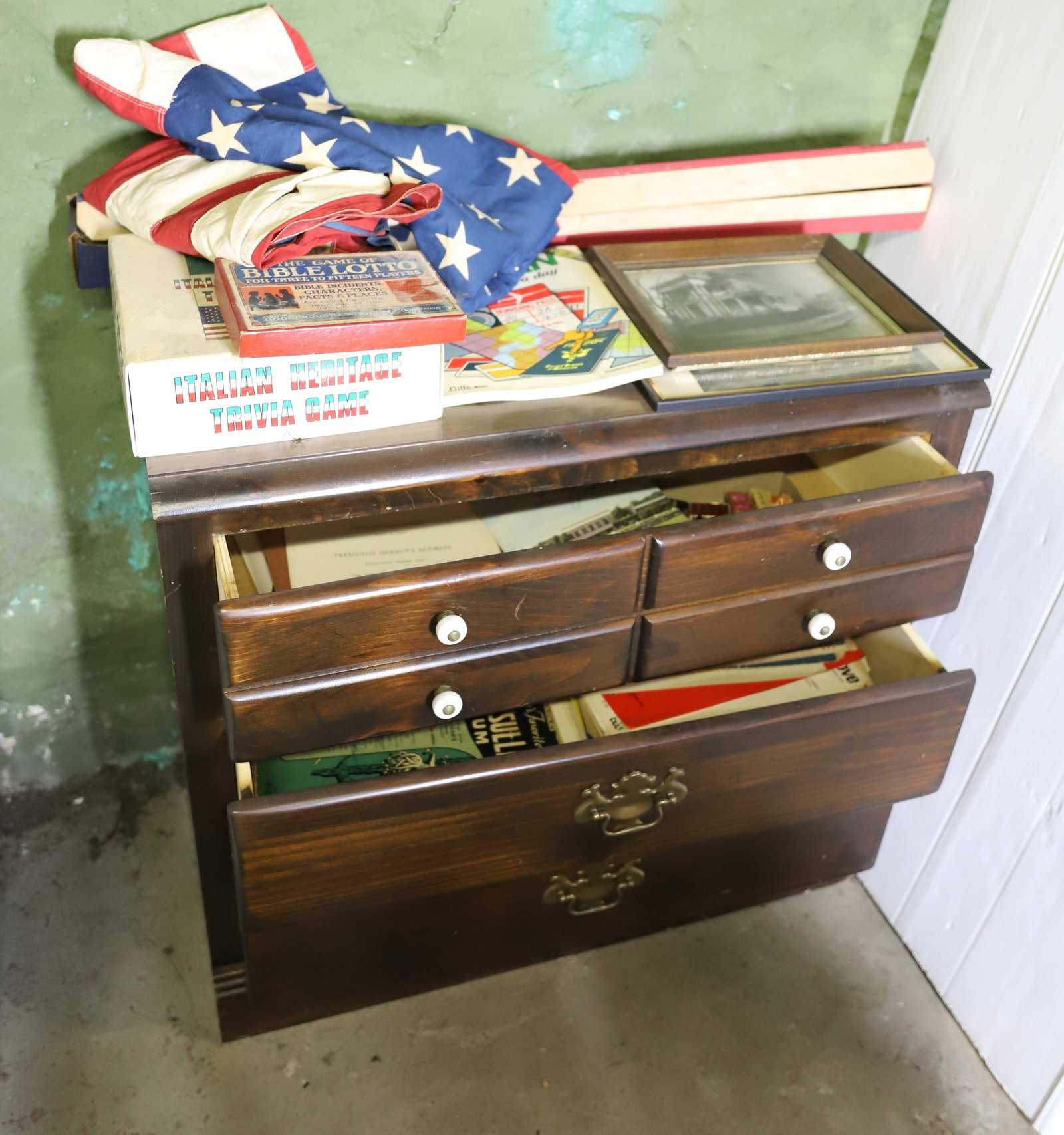 CHEST OF DRAWERS AND CONTENTS: (3)AMERICAN FLAGS, TRIVIA GAME, PINE THREE DRAWER CHEST, SHEET MUSIC, TRAVEL, LANGUAGE BOOK ETC 30" X 32" X 18" PLEASE READ CAREFULLY – THIS IS AN ONSITE ONLINE ONLY AUCTION. The Address is 206 Mark