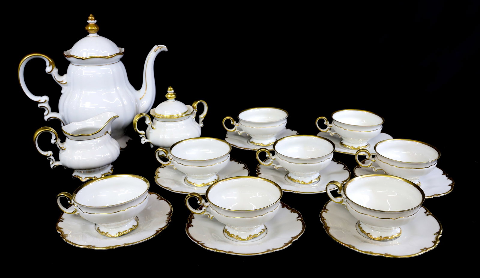 GERMAN HUTSCHENREUTHER TEA SET: GOLD TRIM ON PORCELAIN. INCLUDING: TEAPOT, SUGAR/CREAMER, EIGHT CUPS/SAUCERS. 11" H. PLEASE READ CAREFULLY - Terms for Purchasing and Shipping of Auction Items. Please read carefully before bidding. A