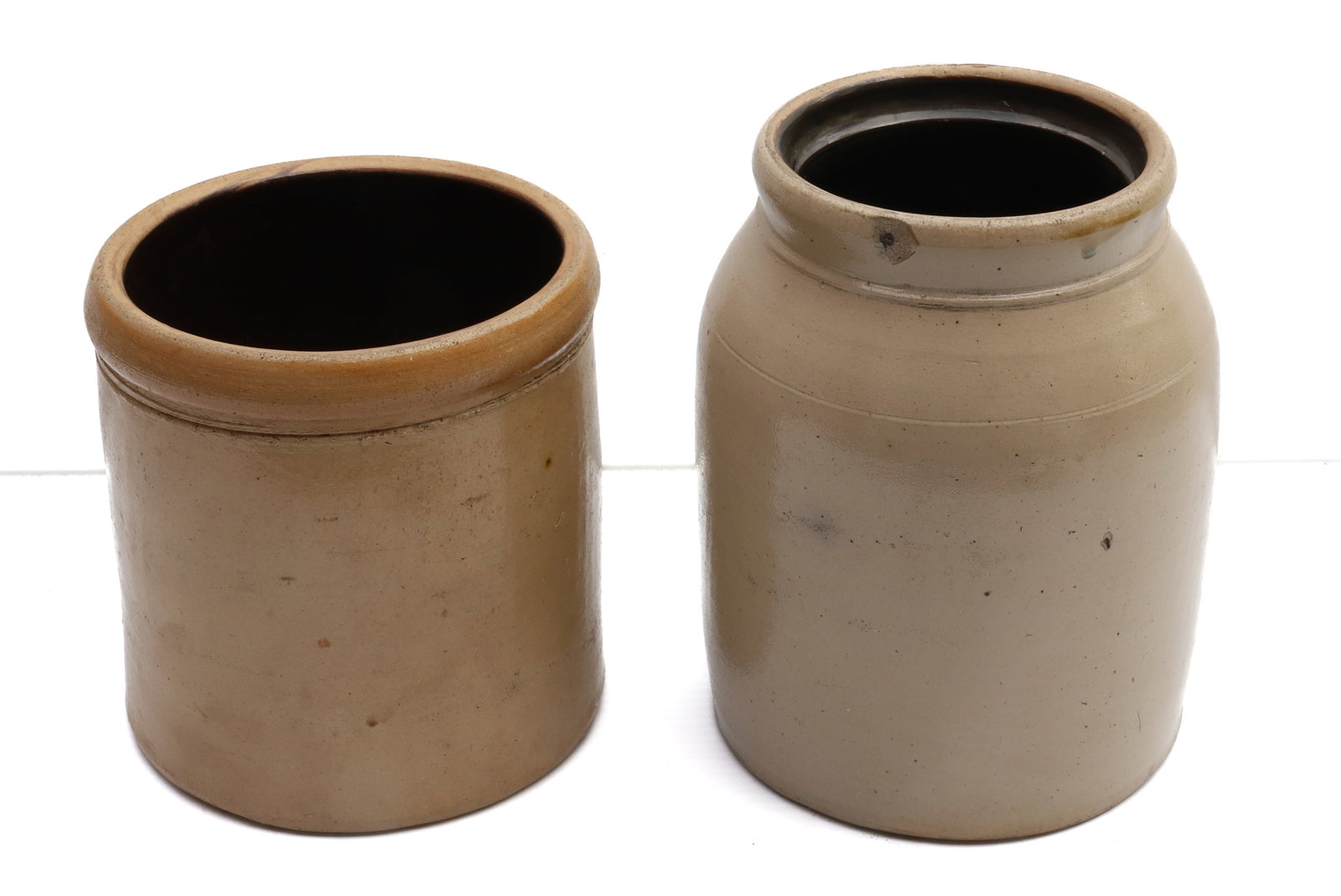 (2) STONEWARE CROCKS: UNMARKED WITH TAN GLAZE - 7 1/2" AND 9 1/2" H Terms: PLEASE READ CAREFULLY -THIS IS AN ONLINE ONLY AUCTION. Terms for Purchasing and Shipping of Auction Items. Please read carefully before bidding. Al