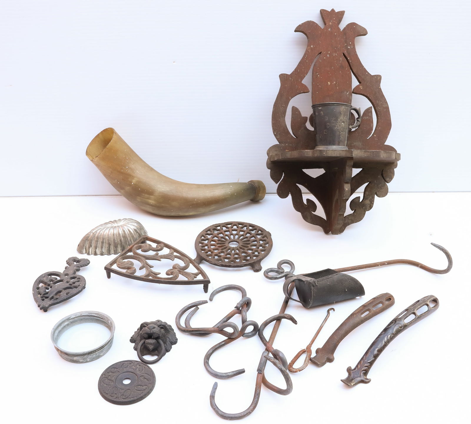 LOT OF CAST IRON AND MORE: CAST IRON TRIVETS, POWDER HORN, HANDLED CUP, WOODEN SHELF, AND MORE Terms: PLEASE READ CAREFULLY -THIS IS AN ONLINE ONLY AUCTION. Terms for Purchasing and Shipping of Auction Items. Please read carefu