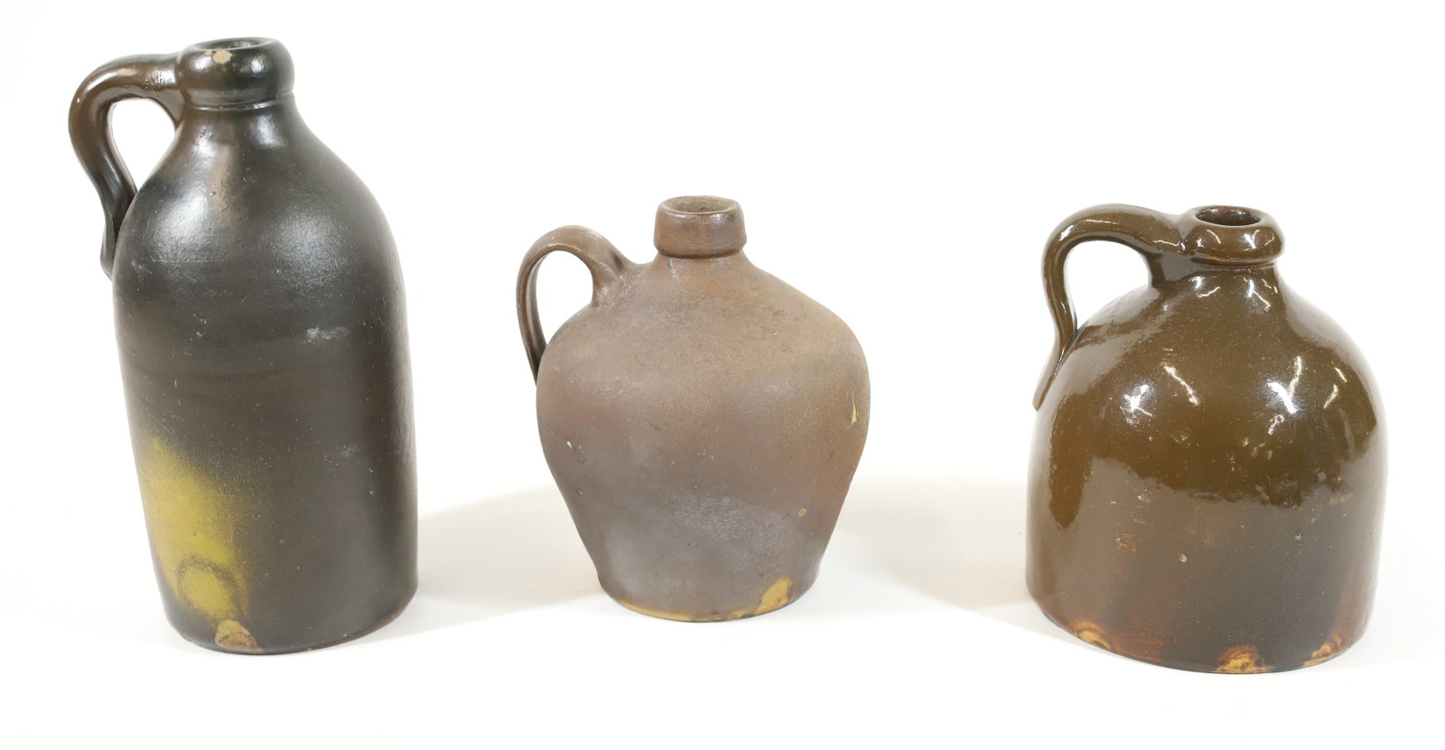 (3) STONEWARE JUGS: VARIOUS BROWN GLAZES AND FORMS. 6 1/4" TO 8 3/4" HEIGHTS. PLEASE READ CAREFULLY -THIS IS AN ONLINE ONLY AUCTION. WE WILL BE TAKING ABSENTEE AND PHONE BIDS ALSO. Terms for Purchasing and Shipping of Au