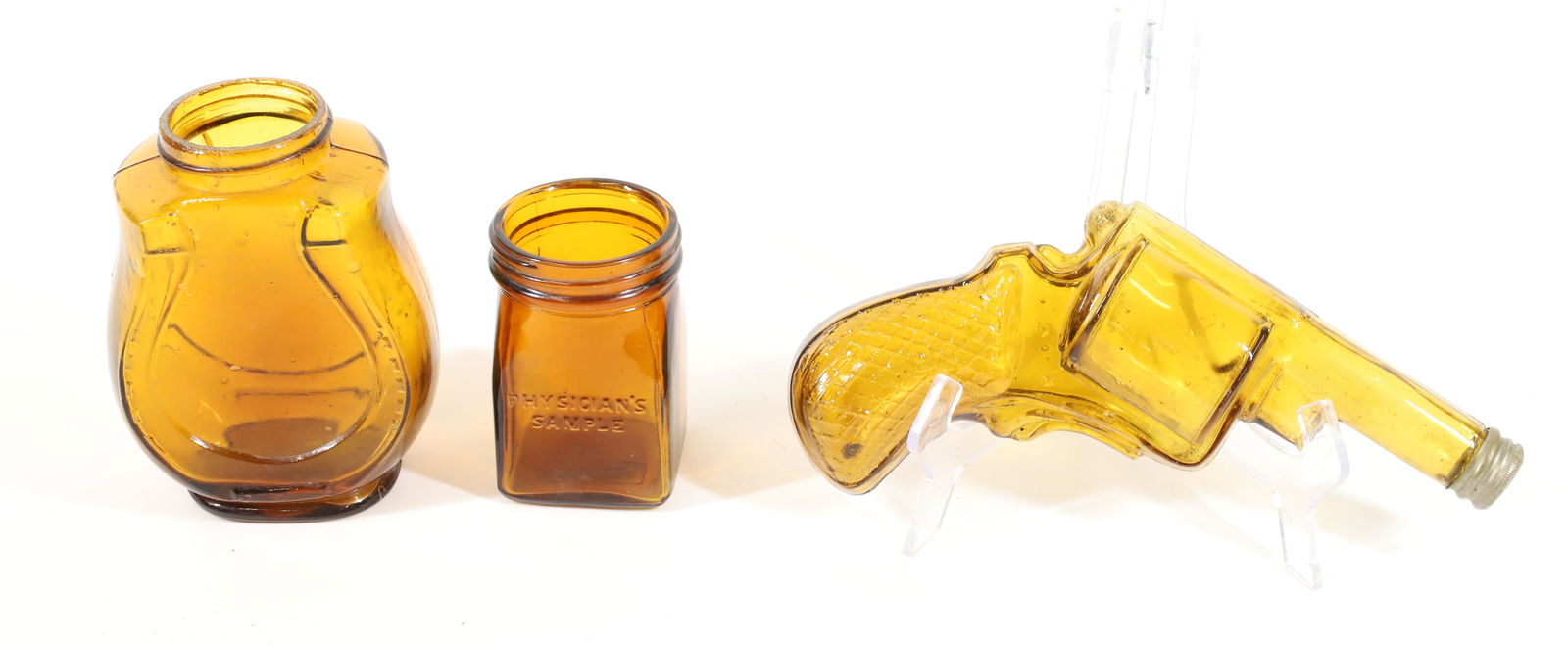 LOT OF AMBER GLASS: INCLUDING: AMBER GLASS PISTOL WITH CAP ON END 7 1/4" L., HORSESHOE JAR AND JAR MRKD. "PHYSICIANS SAMPLE". PLEASE READ CAREFULLY -THIS IS AN ONLINE ONLY AUCTION. WE WILL BE TAKING ABSENTEE AND PHONE BI