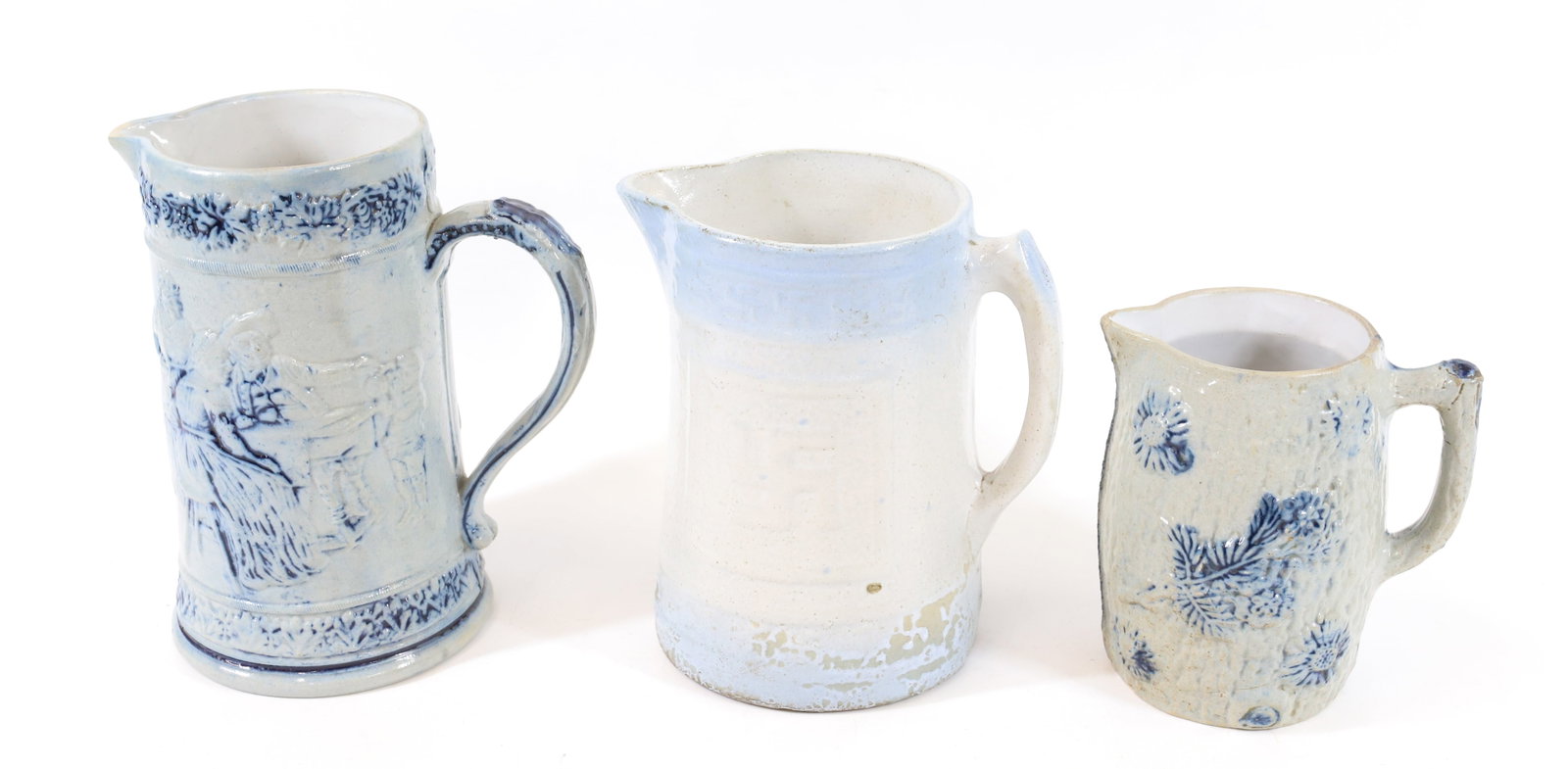 (3) SALT GLAZED STONEWARE PITCHERS: SMALLEST HAS FLORAL DECORATION 6 1/2" H., BLUE/WHITE PITCHER WITH SWASTIKA PATTERN 8 1/4" H. AND LARGEST HAS GROUP OF PEOPLE DRINKING AND STANDING ASIDE KEG. 9 1/4" H. PLEASE READ CAREFULLY -THIS IS A