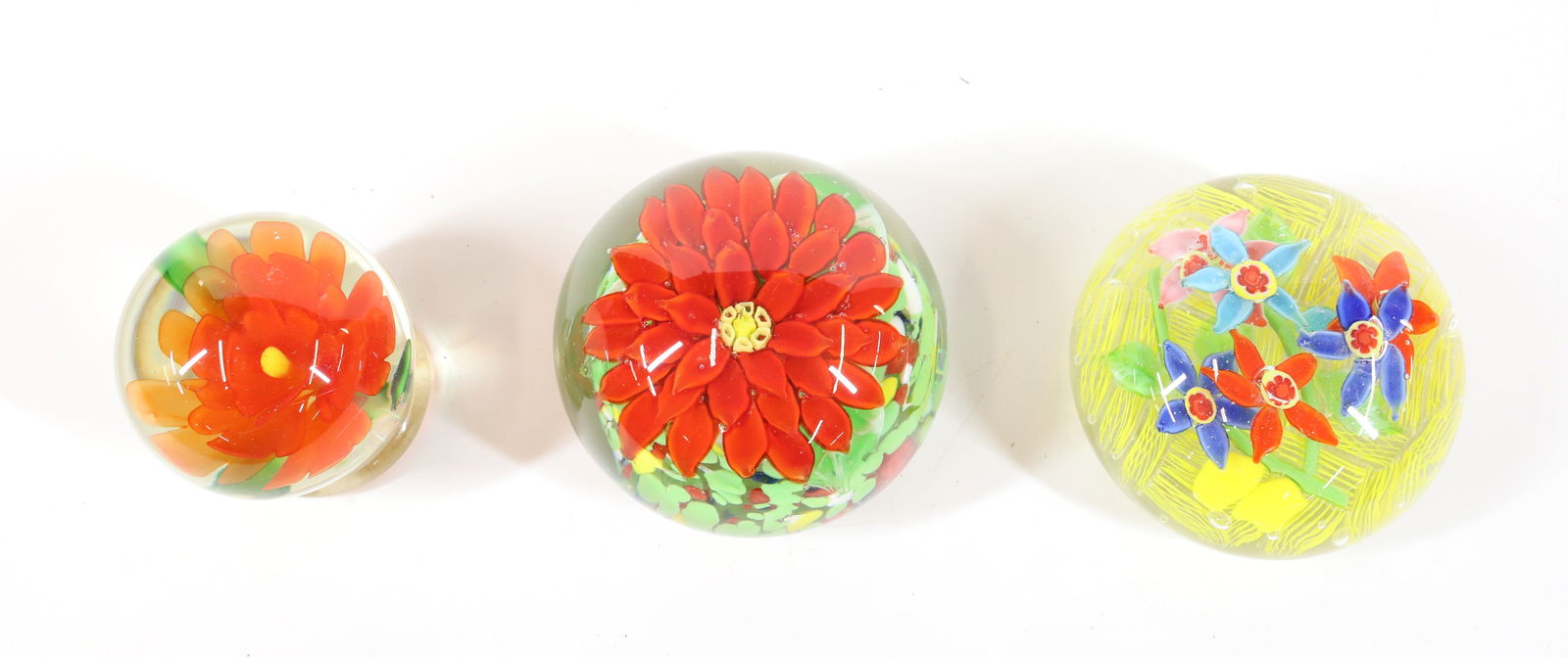 (3) ART GLASS PAPERWEIGHTS: MULTI PETAL RED FLOWER WITH LEAVES AND MULTI COLOR BASE, MULTI PETAL ORANGE FLOWER LEAVES AND APPLIED BASE, STAR FLOWERS OVER YELLOW RIBBON CANES ALL GROUND BASES 2 1/2" TO 3 1/2"H 2 3/4"DIA TO 3 1/2"