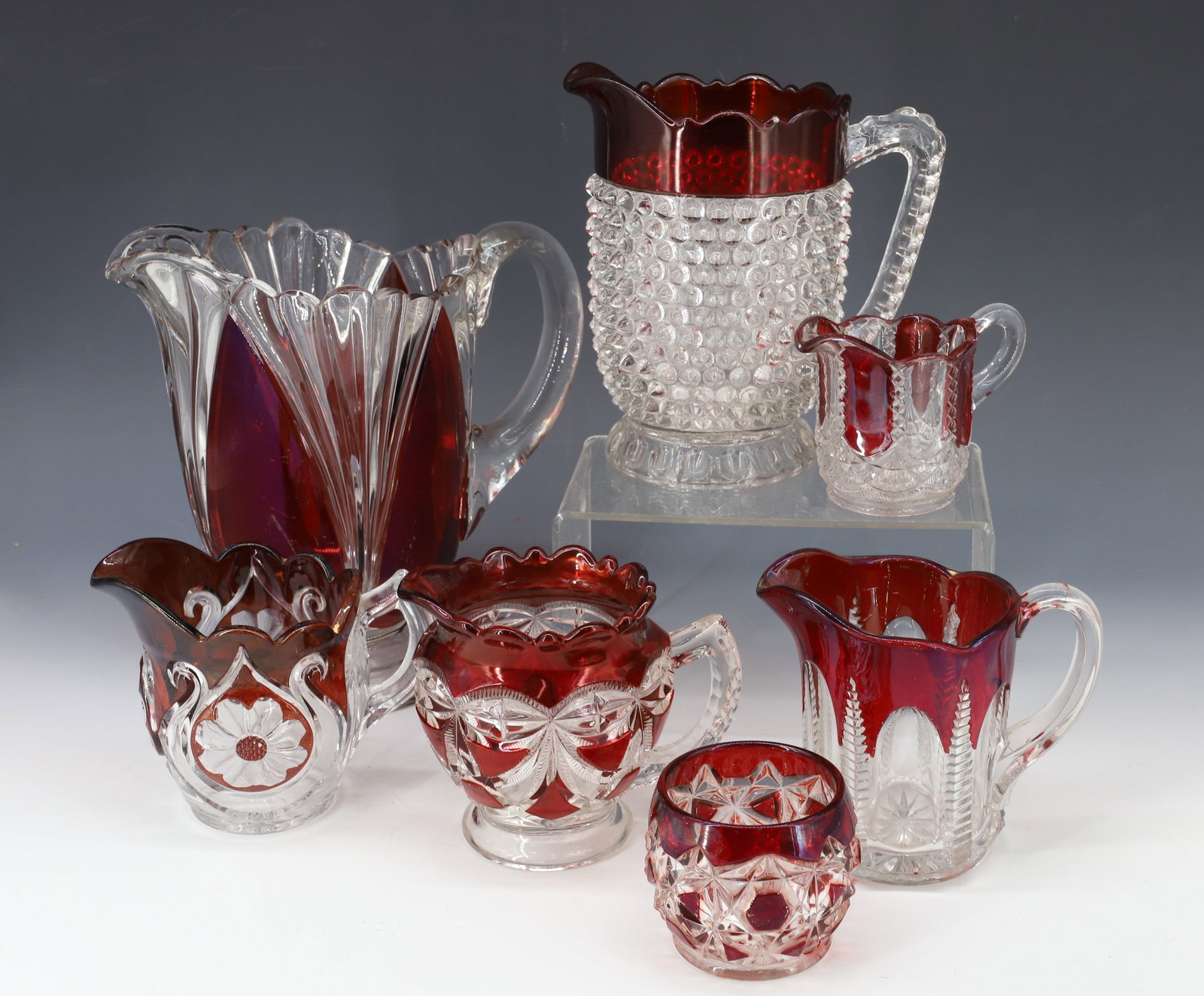 (7) EARLY AMERICAN PRESSED GLASS WITH RUBY DECORATION SUGAR,CREAMER,SPOONER: INCLUDES TWO PITCHERS, FOUR CREAMERS AND OPEN SUGAR BOWL 2 1/2" TO 9" PLEASE READ CAREFULLY - Terms for Purchasing and Shipping of Auction Items. Please read carefully before bidding. All payments for