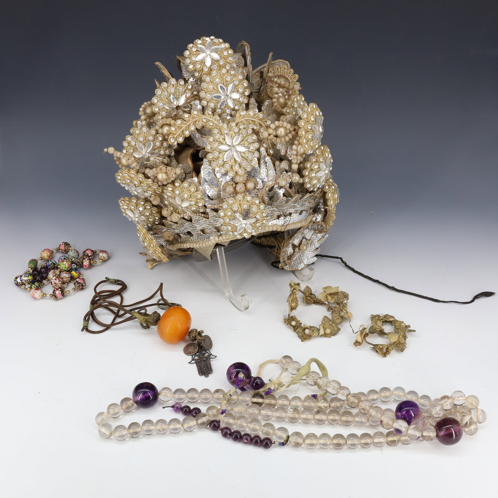 (4) 1920S CHINESE OPERA HAT: ORNATE WITH SEQUINS,TASSELS, RHINESTONES, WITH MURANO GLASS BEAD NECKLACE, LARGE NECKLACE WITH CLEAR AND AMETHYST GLASS BEADS , ASIAN NECKLACE WITH SILVER ORNAMENTS AND SYNTHETIC AMBER HAT 10X10" DIA,