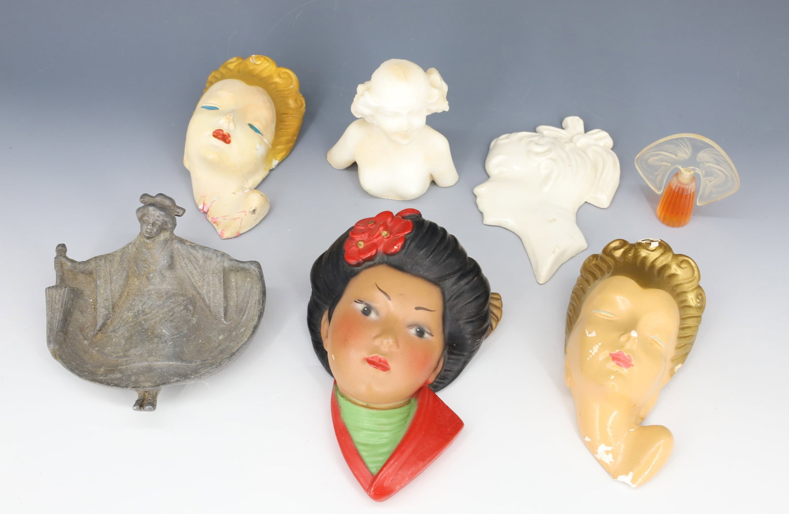 (7) LALIQUE PERFUME, CHALKWARE HEAD PLAQUES, NAUGHTY ASHTRAY: LALIQUE PERFUME FULL BOTTLE PLASTIC STOPPER, ALUMINUM NAUGHTY ASHTRAY, THREE CHALKWARE HEAD PLAQUES, POTTERY PLAQUE AND SALT FIGURINE 3" TO 6" PLEASE READ CAREFULLY - Terms for Purchasing and Shipping