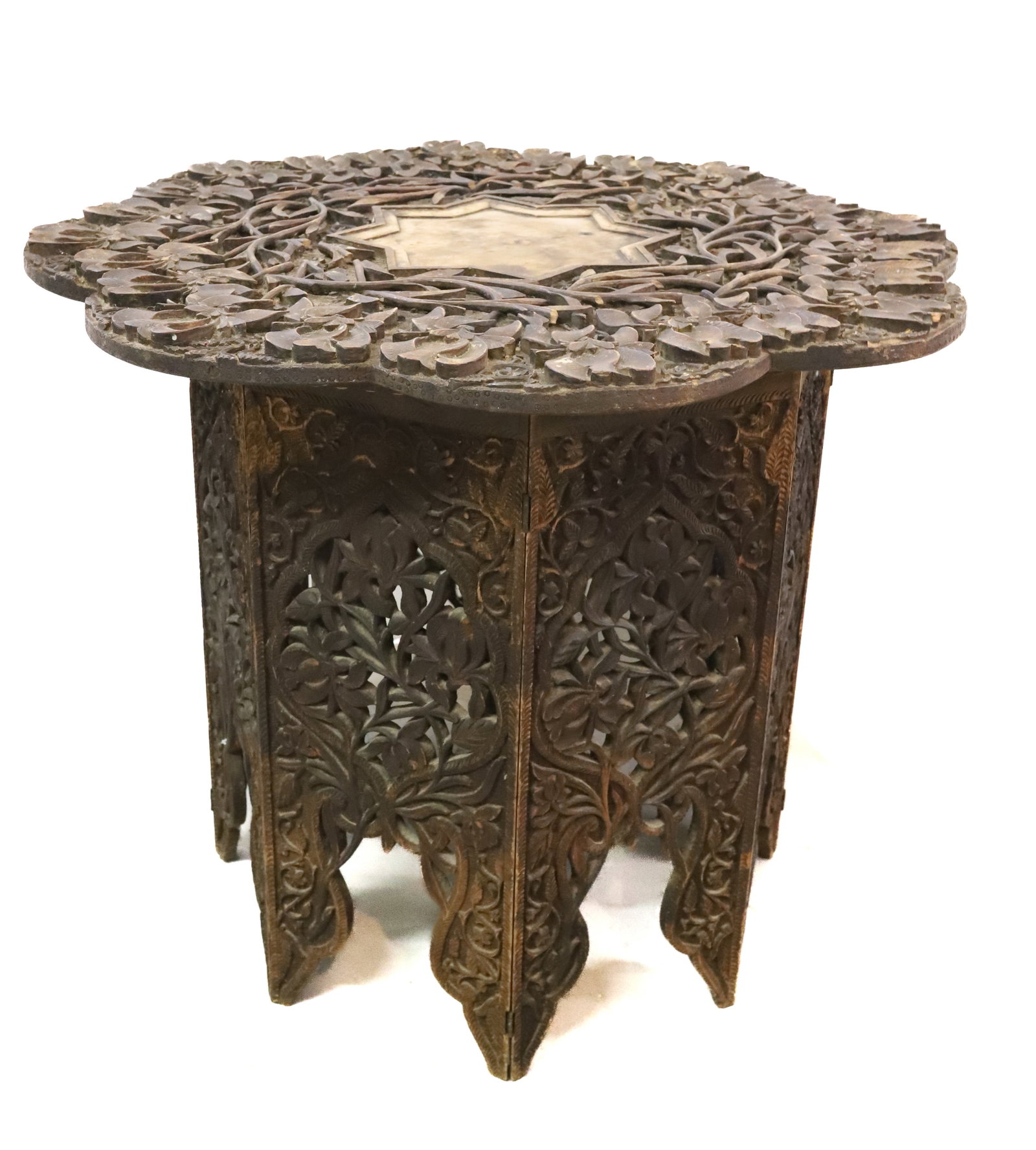 MOROCCAN CARVED SIDE TABLE: SCALLOPED CARVED TOP WITH CENTRAL STAR. FOLD UP PANELED BASE. 25 1/2" X 30". PLEASE READ CAREFULLY - Terms for Purchasing and Shipping of Auction Items. Please read carefully before bidding. All payme