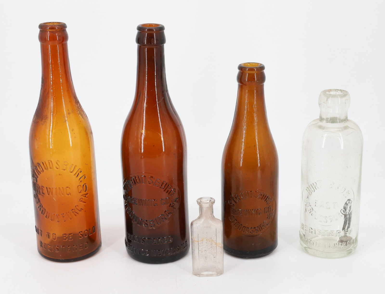 LOT OF STROUDSBURG, PA BOTTLES: INCLUDING : THREE AMBER STROUDSBURG BREWING COMPANY AND BURT BROS. EAST STROUDSBURG WITH SMALL "RED CROSS PHARMACY, EAST STROUDSBURG" BOTTLE. 3" TO 9 1/4" H. Terms: PLEASE READ CAREFULLY - Terms for P