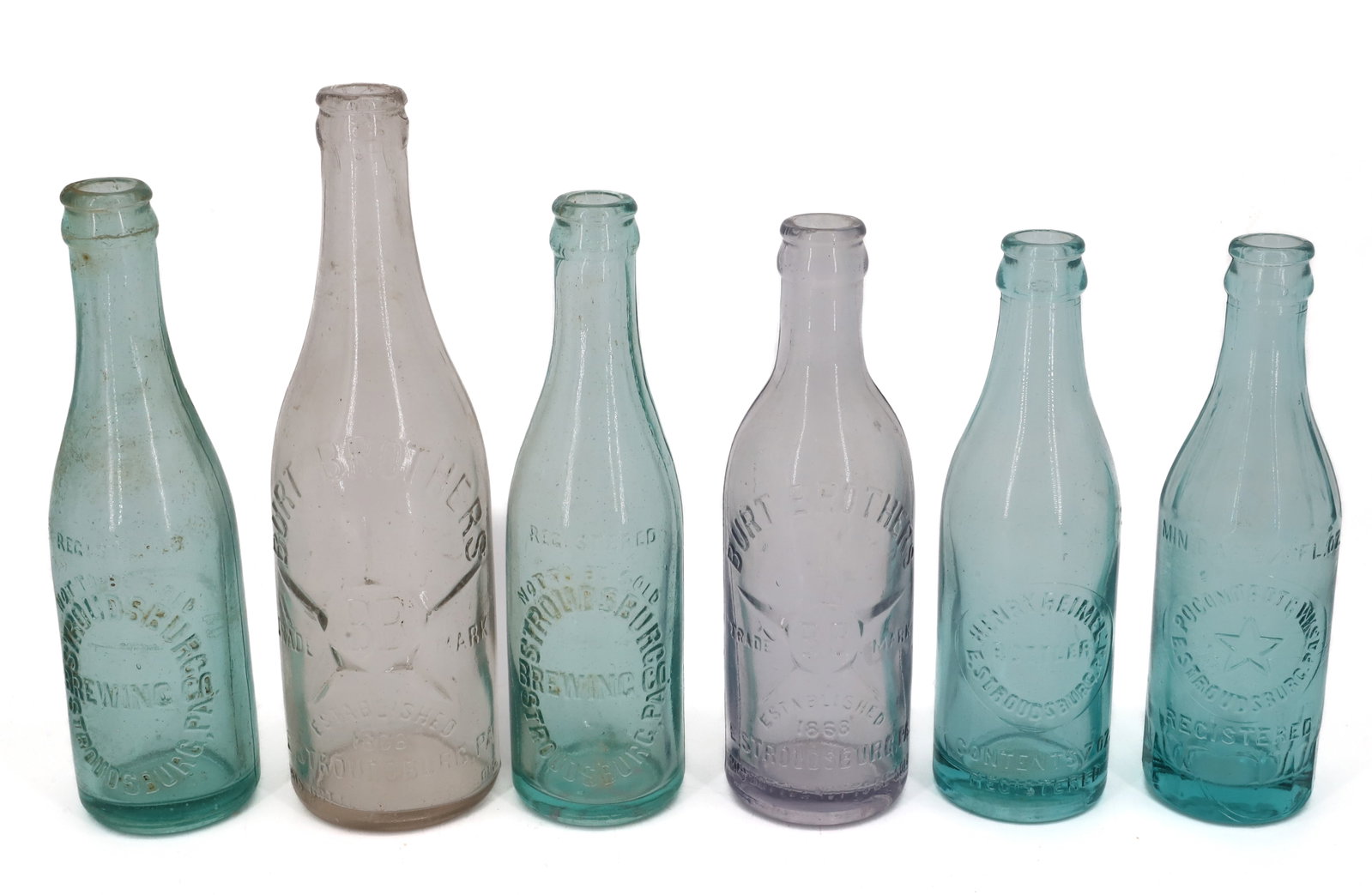 LOT OF STROUDSBURG, PA BOTTLES: INCLUDING: TWO STROUDSBURG BREWING COMPANY IN GREEN. FOUR EAST STROUDSBURG BOTTLES INCLUDING: (2) BURT BROTHERS, HENRY REIMEL AND POCONO BOTTLING WORKS. 7 1/2" TO 9 1/4". Terms: PLEASE READ CAREFULLY 