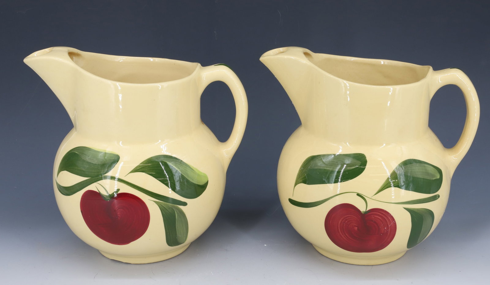 (2) WATT WARE PITCHERS: APPLE PATTERN. 8" H. PLEASE READ CAREFULLY - Terms for Purchasing and Shipping of Auction Items. Please read carefully before bidding. All payments for purchases will be made through LiveAuctioneers.c