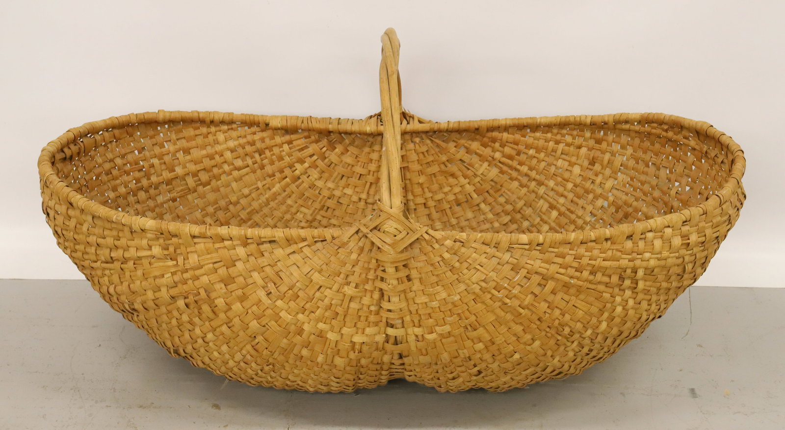LARGE WOVEN GATHERING BASKET: BUTTOCKS SHAPE WITH WOVEN HANDLE. 39" L. PLEASE READ CAREFULLY - Terms for Purchasing and Shipping of Auction Items. Please read carefully before bidding. All payments for purchases will be made throu
