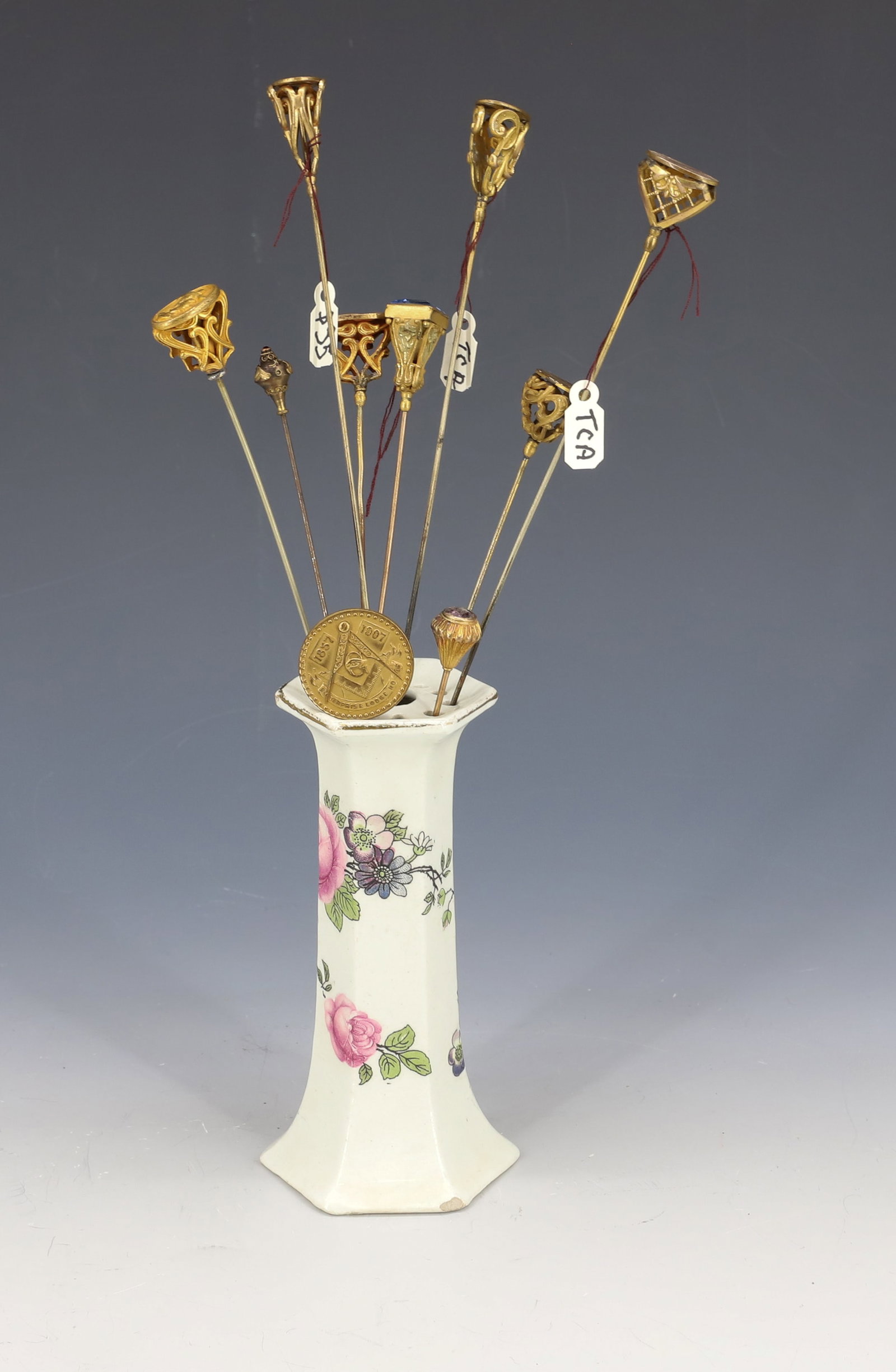 (9) HATPINS AND HOLDER: (2) METAL CAMEOS, (4) OVAL MONOGRAMS, MASONIC, ETRUSCAN WORK WITH RED STONE, BLUE STONE AND DAMAGED AMETHYST HOLDER UNMARKED 11" LONGEST PLEASE READ CAREFULLY - Terms for Purchasing and Shipping of Au