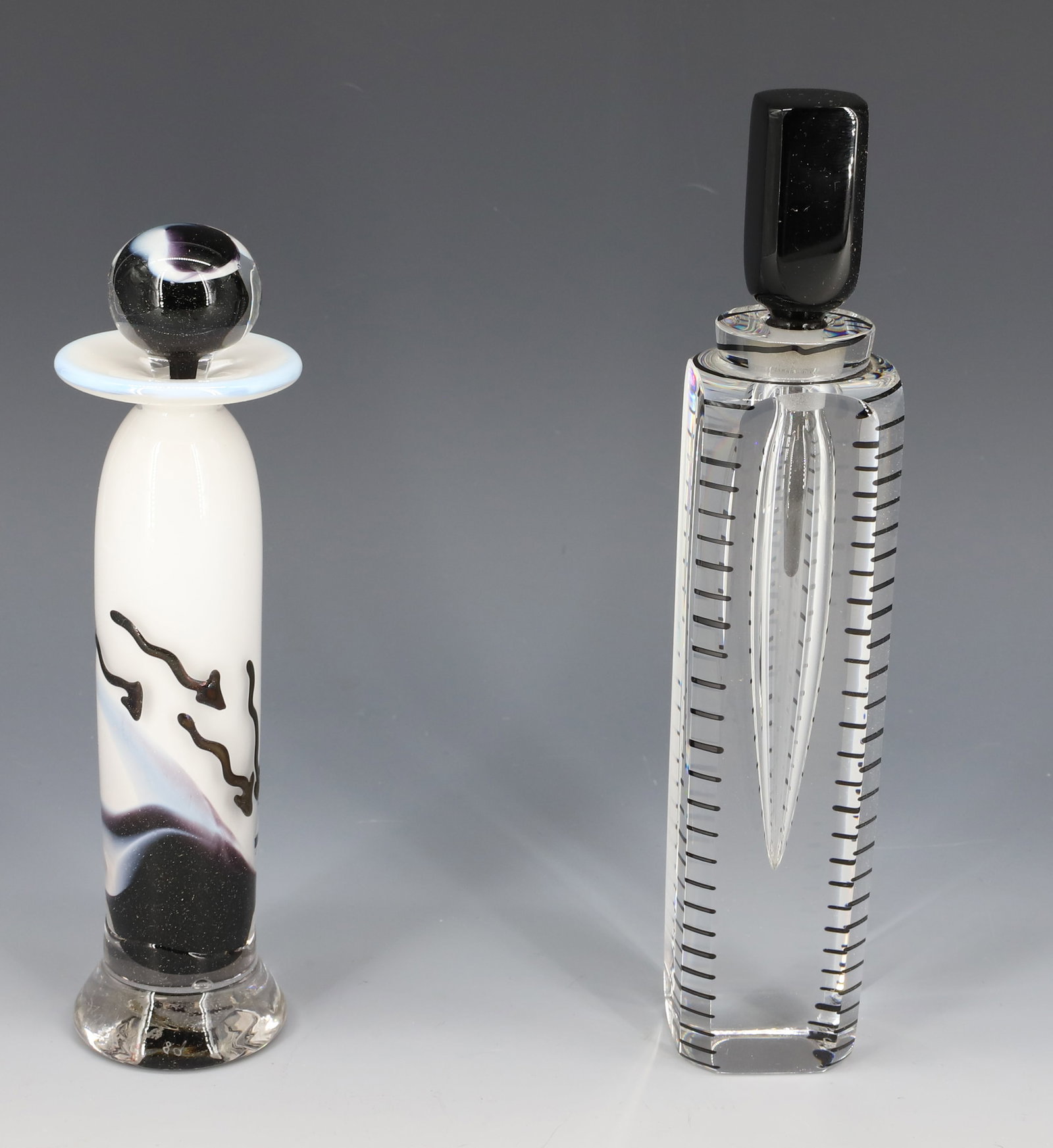 (2) ART GLASS PERFUME BOTTLES: BLACK/WHITE/CLEAR SGND/DATED "GILVEY, 89". 6 3/4" H. WITH, CLEAR / BLACK TALLER EXAMPLE MRKD. CORREIA, 1987 L.E. 4/200. 8" H. PLEASE READ CAREFULLY - Terms for Purchasing and Shipping of Auction Items