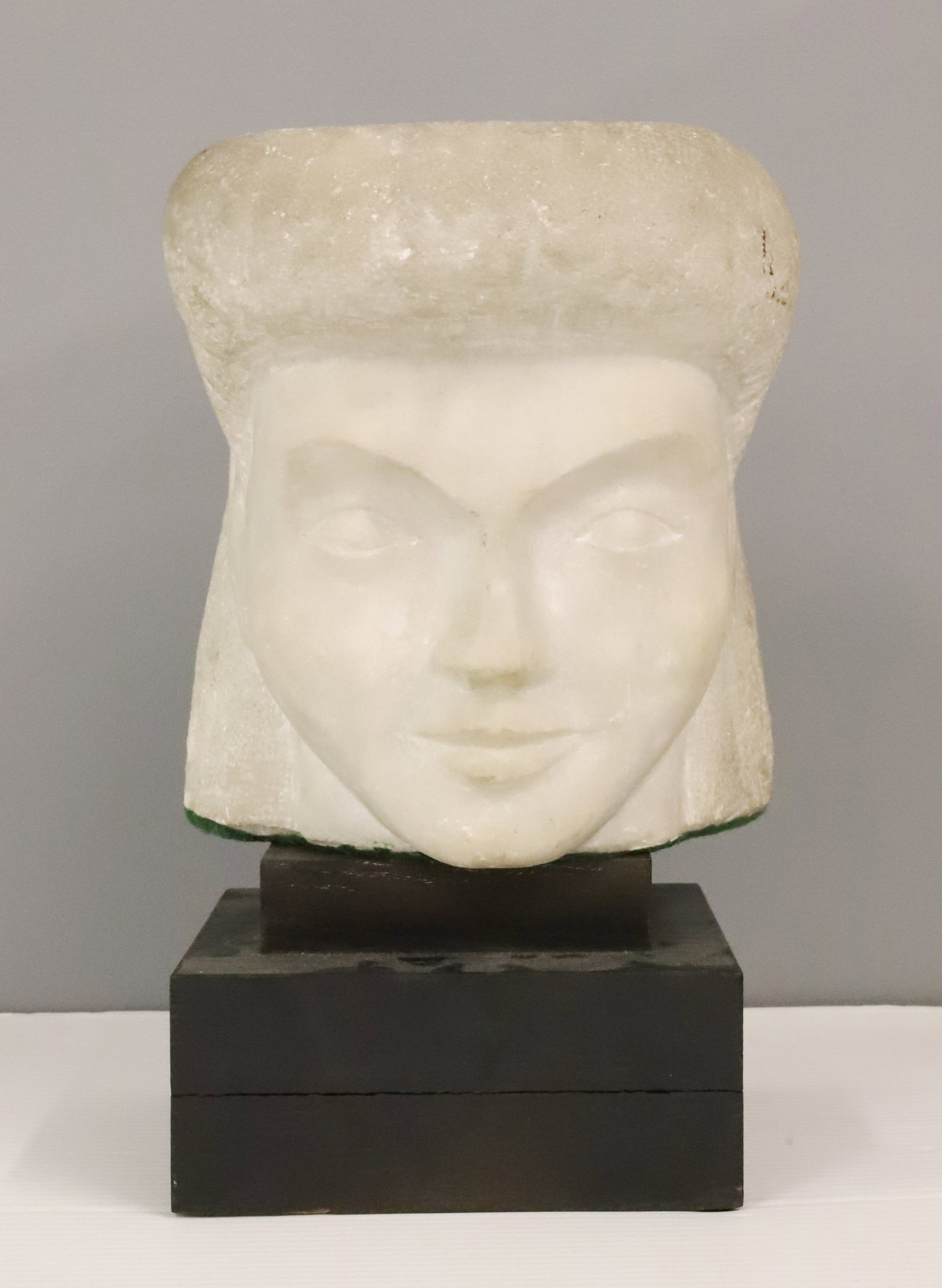 CARVED MARBLE HEAD: HEAD OF A GIRL RESTING ON WOODEN DISPLAY BASE. UNSIGNED. HEAD IS 8 1/2" X 8 1/4". HEAVY.