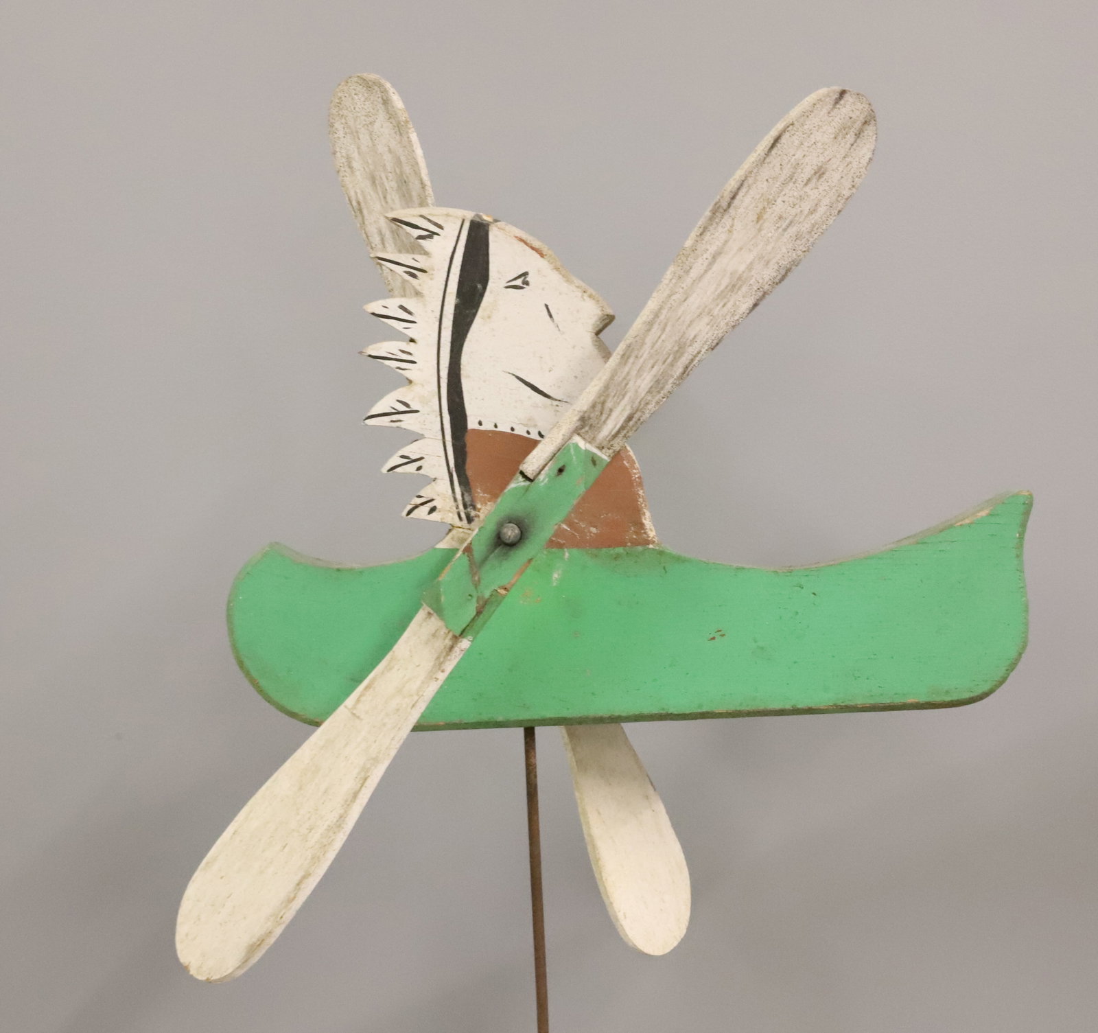 PAINTED INDIAN WHIRLIGIG: WOOD PAINTED INDIAN IN CANOE. MOUNTED ON WOODEN BASE. 30" X 13 1/2" L.