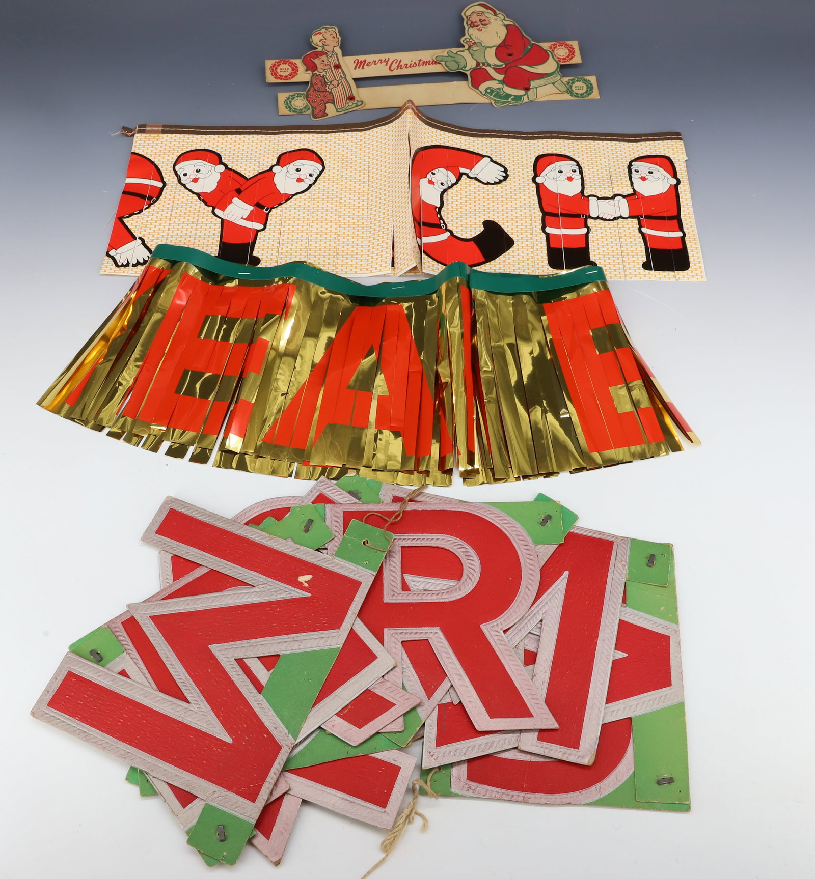 LOT OF VINTAGE CHRISTMAS DECORATIONS: INCLUDING: 1952 CARDBOARD SANTA WITH KIDS 10 1/2" L. (SOME TAPE REPAIR ON BACK), "MERRY CHRISTMAS" BANNER (LETTERS 5 3/4" H.), "MERRY CHRISTMAS" SANTA BANNER AND GOLD/GREEN/RED FRINGED BANNER. PLEASE 