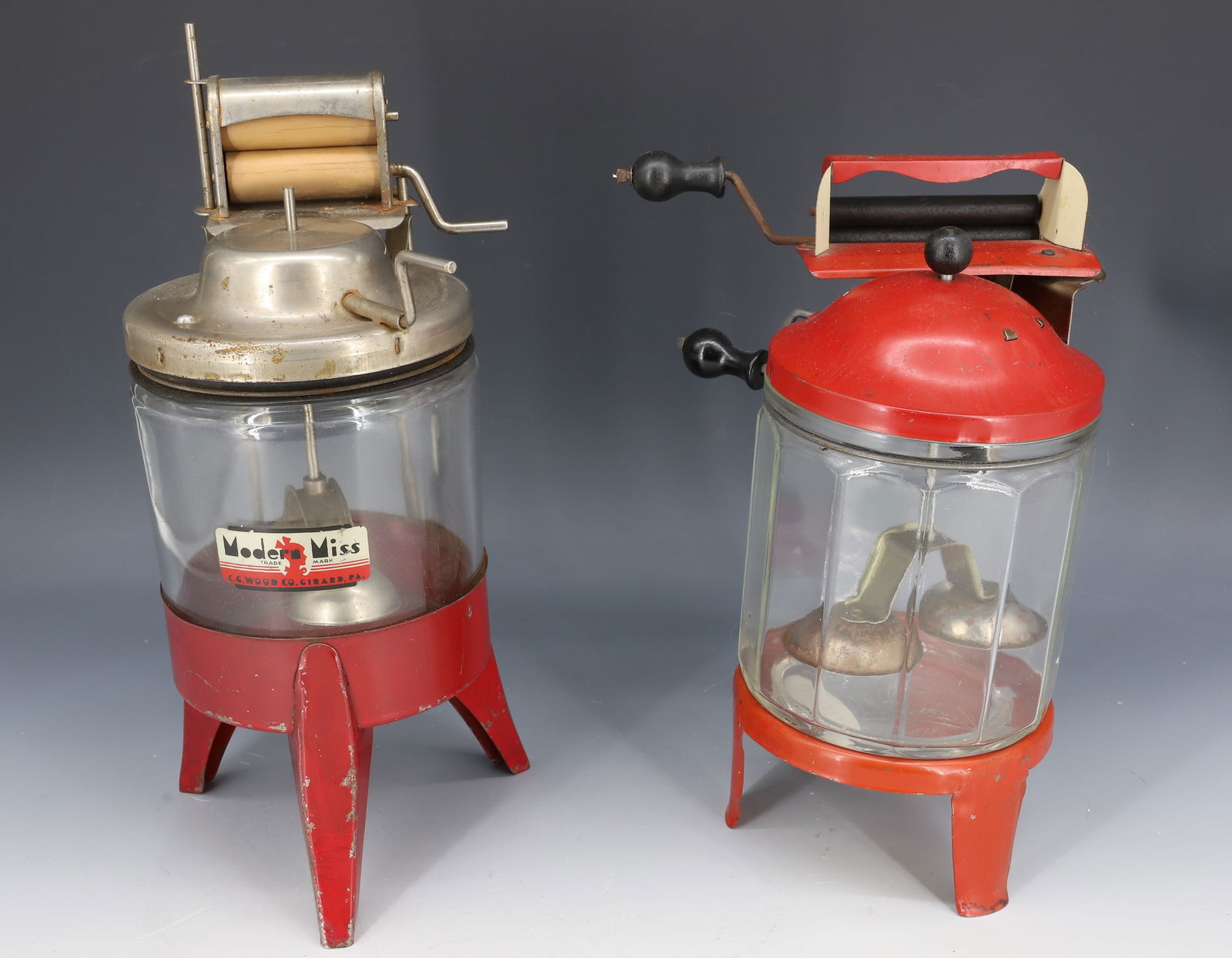 (2) TOY WASHING MACHINES: GLASS AND PAINTED METAL. "MODERN MISS" AND "WOLVERINE". LARGEST WITH ORIGINAL LABEL 11 1/2" H. PLEASE READ CAREFULLY - Terms for Purchasing and Shipping of Auction Items. Please read carefully before