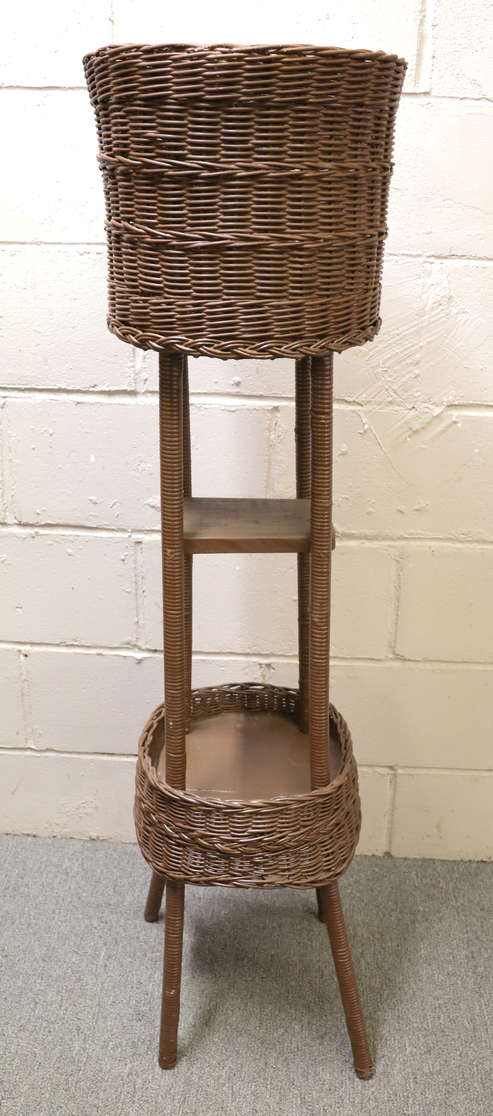 PAINTED WICKER-STYLE PLANT STAND: BROWN PAINTED CANING. RIBBED LEGS HOLDING TWO TIERS. 48 1/2" H. PLEASE READ CAREFULLY - Terms for Purchasing and Shipping of Auction Items. Please read carefully before bidding. Hartzell?s Auction Gal