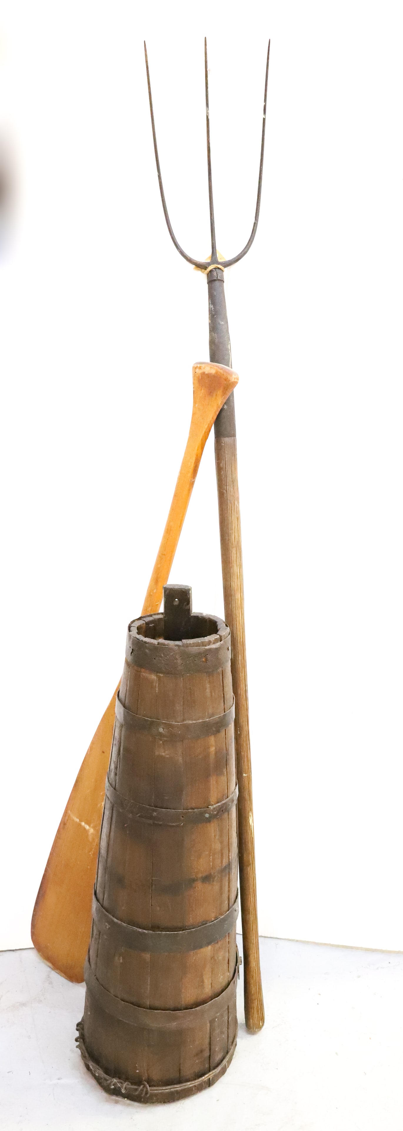 BUTTER CHURN, PITCHFORK AND OAR: TAPERED WOODEN CHURN BASE WITH IRON BANDING 30" H. (MISSING ONE BAND), THREE-PRONG PITCHFORK 60" H. AND WOODEN PADDLE. PLEASE READ CAREFULLY - Terms for Purchasing and Shipping of Auction Items. Pleas