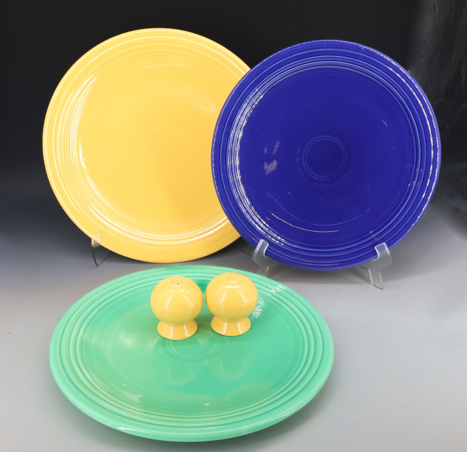 LOT OF VINTAGE FIESTA WARE: SALT / PEPPER SHAKERS WITH THREE CHOP PLATES 12 1/4" TO 14 1/4" DIAMETERS. TWO ARE MRKD. PLEASE READ CAREFULLY - Terms for Purchasing and Shipping of Auction Items. Please read carefully before biddin