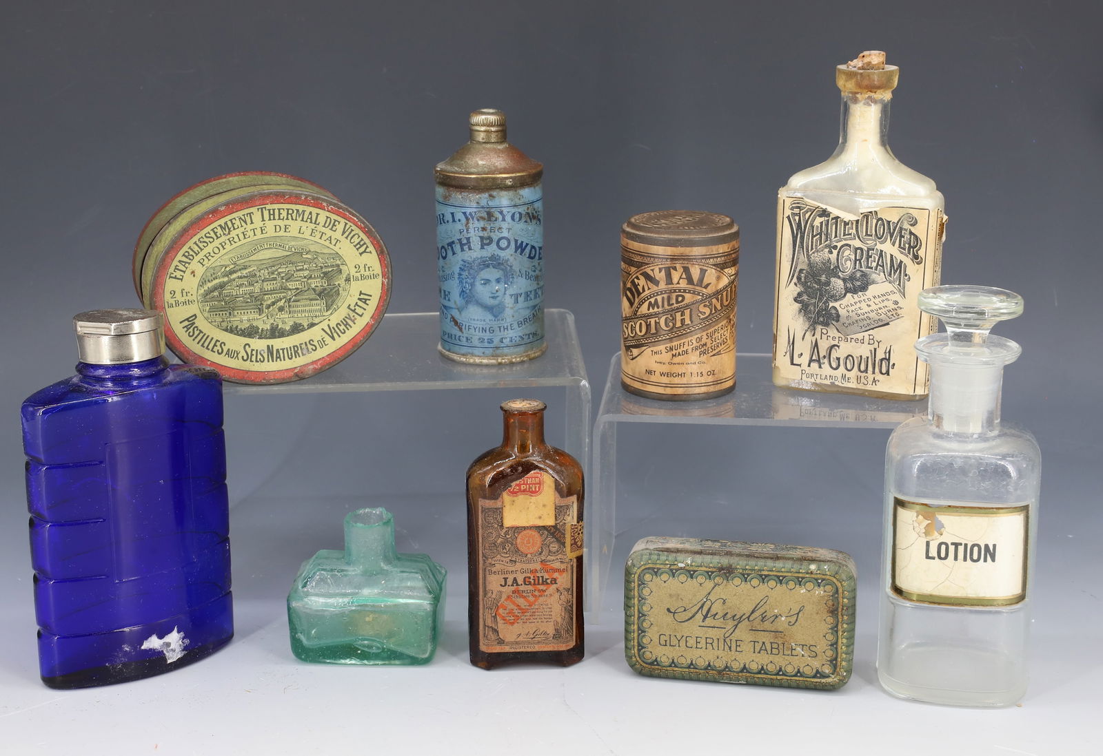 LOT OF ADVERTISING BOTTLES / TINS: TINS INCLUDE: DENTAL SCOTCH SNUFF, PASTILLES OVAL TIN 3 3/8" D., DR. LYON'S TOOTH POWDER AND MORE. GLASS BOTTLE WITH PAPER LABEL "WHITE CLOVER CREAM, GOULD, PORTLAND, ME. PLUS, BOAT-SHAPE INKWELL. 2"