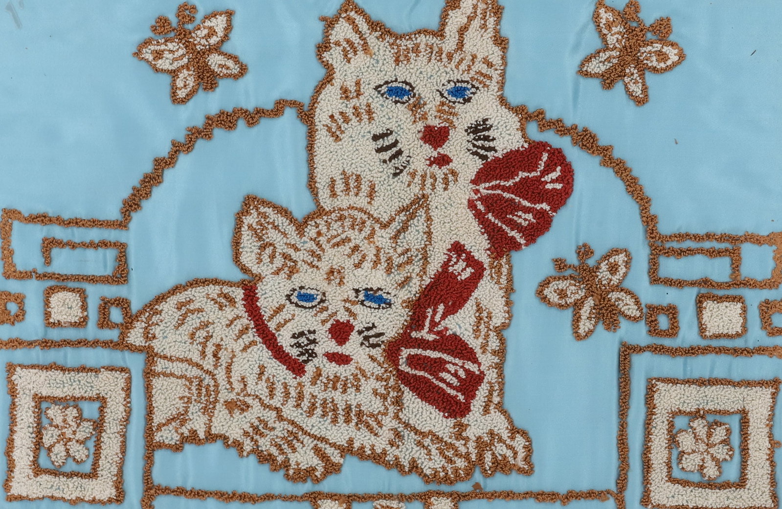FRAMED TEXTILE OF CATS: HANDWORK DONE ON BLUE SATIN BACKING. SHOWS TWO CATS WITH BLUE EYES AND RED BOWS. BROWN AND WHITE FLORAL AND BUTTERFLIES SURROUNDING. TOTAL FRAMED SIZE 14 1/2" X 19 1/2". PLEASE READ CAREFULLY - Terms 