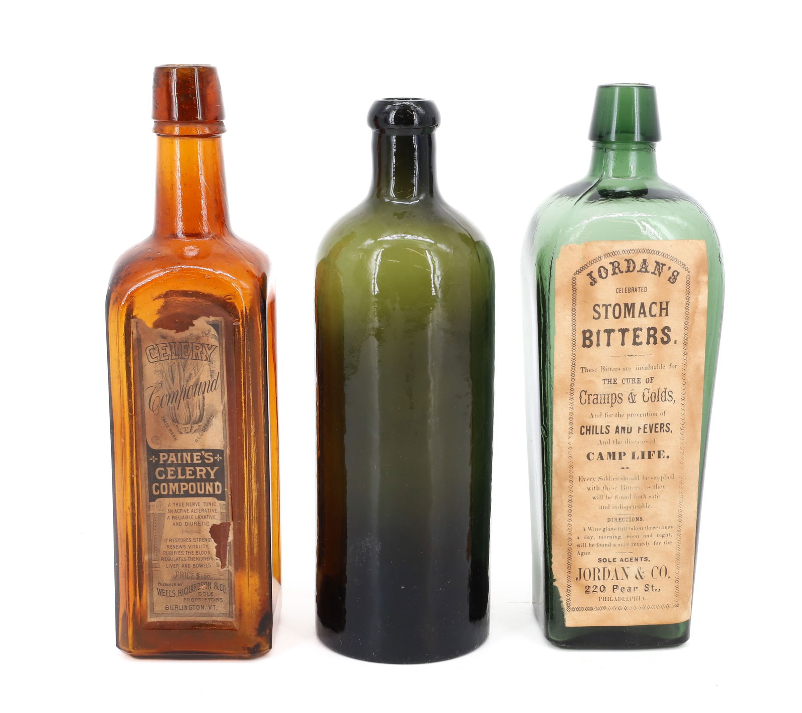 (2) ANTIQUE BOTTLES WITH PAPER LABELS: JORDAN'S STOMACH BITTERS, PHILADELPHIA IN GREEN 9 1/2" H. AND "PAINE'S CELERY COMPOUND" IN AMBER 9 3/4" H. PLUS, DARK OLIVE BOTTLE EMBOSSED ON BOTTOM. PLEASE READ CAREFULLY - Terms for Purchasing and