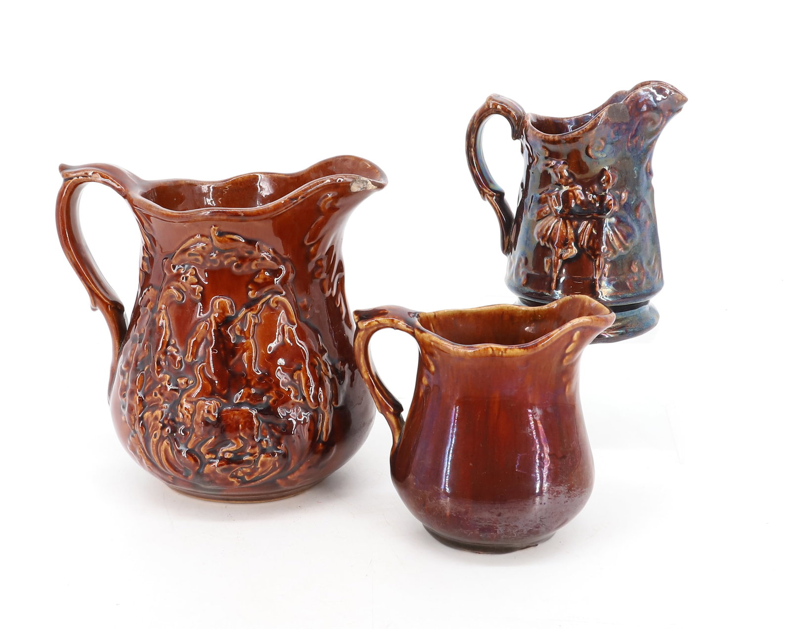 (3) ROCKINGHAM GLAZE PITCHERS: EMBOSSED DECORATION. 5" TO 7 1/4" HEIGHTS. LARGEST HAS HUNTER AND DOG ON EITHER SIDE. PLEASE READ CAREFULLY - Terms for Purchasing and Shipping of Auction Items. Please read carefully before bidding. 