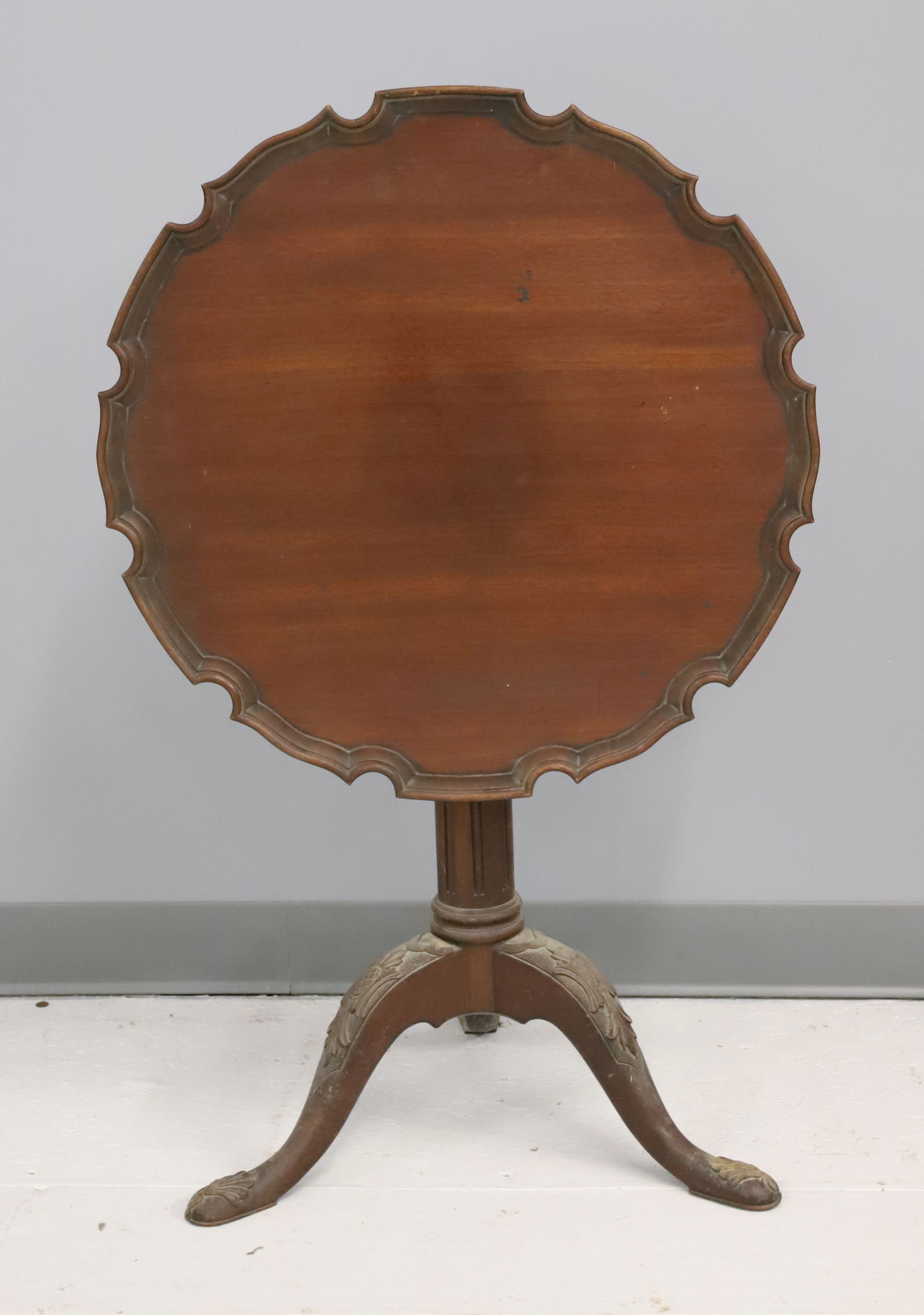 MAHOGANY TEA TABLE: TILT-TOP TABLE WITH PIE CRUST TOP WITH CARVED COLUMN AND CARVED TRIPOD FEET. 24 1/2" X 23 1/2". 37 1/2" H. WHEN TOP FLIPPED UP. PLEASE READ CAREFULLY - Terms for Purchasing and Shipping of Auction Ite