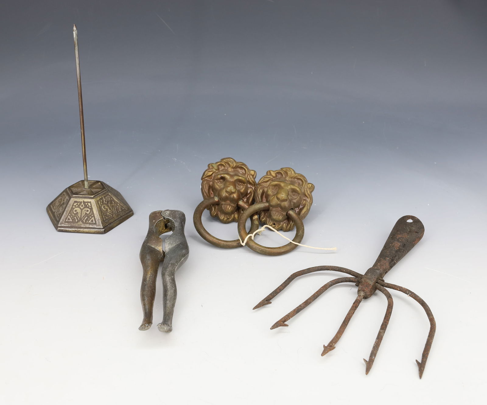 LOT OF CAST IRON AND BRASS ITEMS: INCLUDING: RECEIPT SPINDLE, EEL GIG, PAIR OF BRASS LION HEADS WITH RINGS. PLUS, ALUMINUM LEGS NUTCRACKER 5 1/2" L. PLEASE READ CAREFULLY - Terms for Purchasing and Shipping of Auction Items. Please re