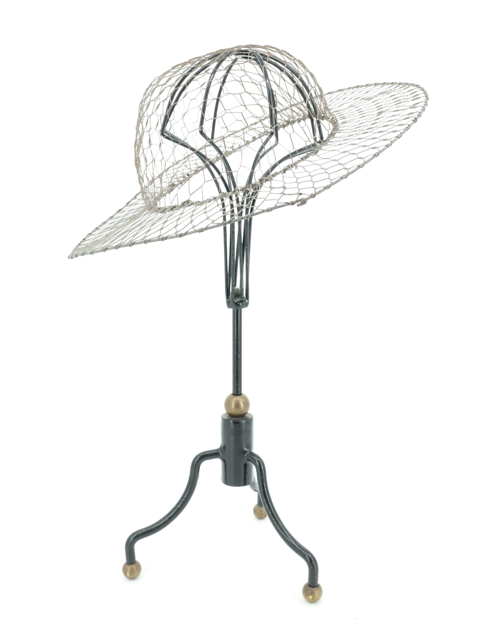 CAST IRON HAT STAND W/ WIRE HAT FORM: PAINTED BLACK IRON WITH BRASS BALLS. 19 1/4" H. WIRE HAT FORM 13 3/4" D. PLEASE READ CAREFULLY - Terms for Purchasing and Shipping of Auction Items. Please read carefully before bidding. Hartzell̵