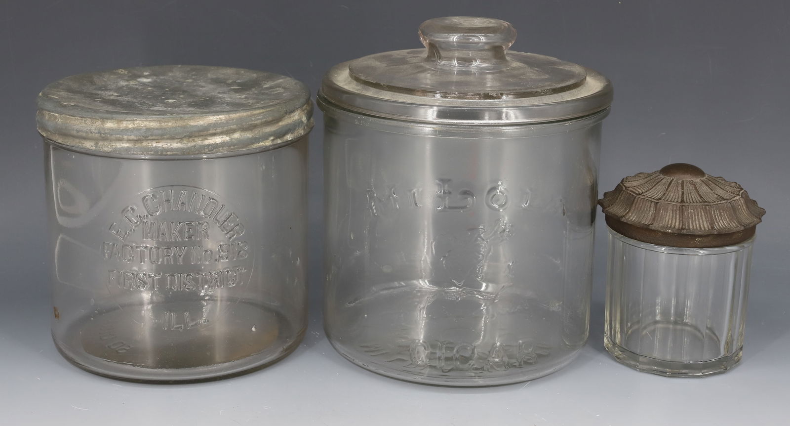 LOT OF CIGAR / TOBACCO JARS: LARGEST "MILOLA CIGAR" EMBOSSED ON SIDE. 6 3/4" X 5 7/8", "E.C. CHANDLER" WITH METAL LID (ILLINOIS) AND SMALL JAR WITH NICE CAST IRON LID. PLEASE READ CAREFULLY - Terms for Purchasing and Shipping of