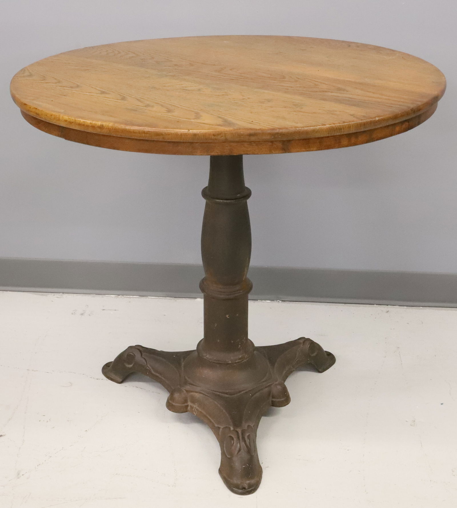 ICE CREAM PARLOR TABLE: ROUND WOODEN TOP WITH EMBOSSED CAST IRON BASE. 28 1/2" X 30". PLEASE READ CAREFULLY - Terms for Purchasing and Shipping of Auction Items. Please read carefully before bidding. Hartzell’s Auction
