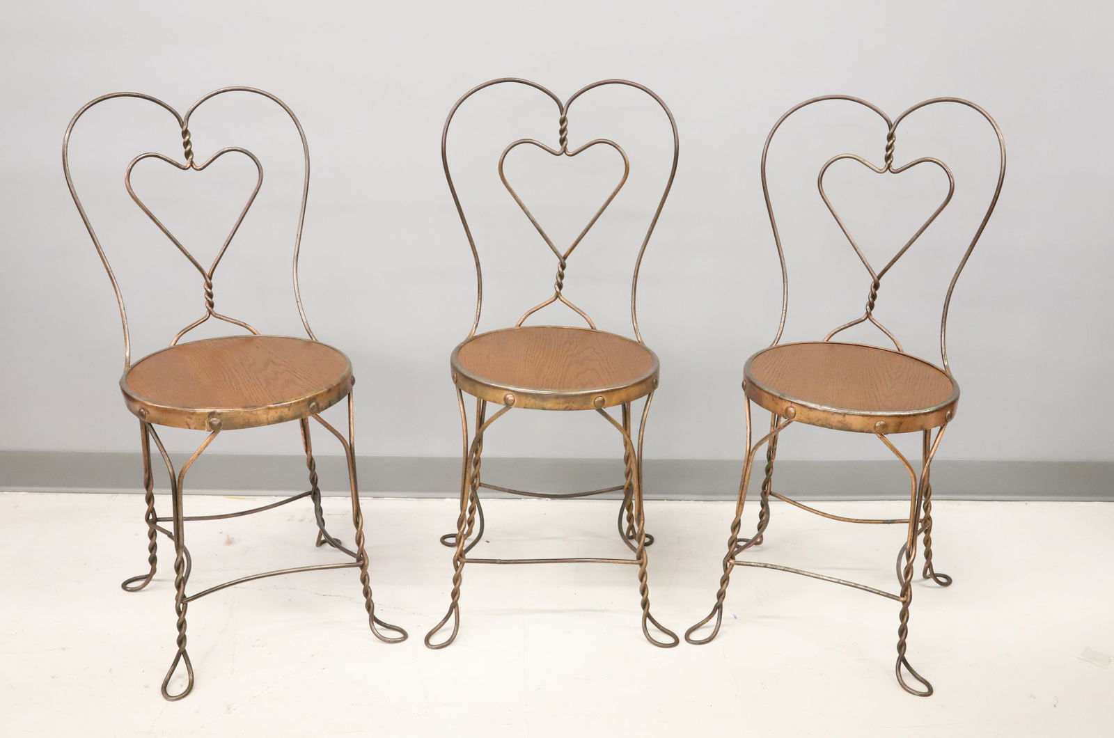(3) ICE CREAM PARLOR CHAIRS: BENT WIRE WITH HEART MOTIF IN BACKS. FAUX COPPER FINISH. PLEASE READ CAREFULLY - Terms for Purchasing and Shipping of Auction Items. Please read carefully before bidding. Hartzell’s Auction Gall