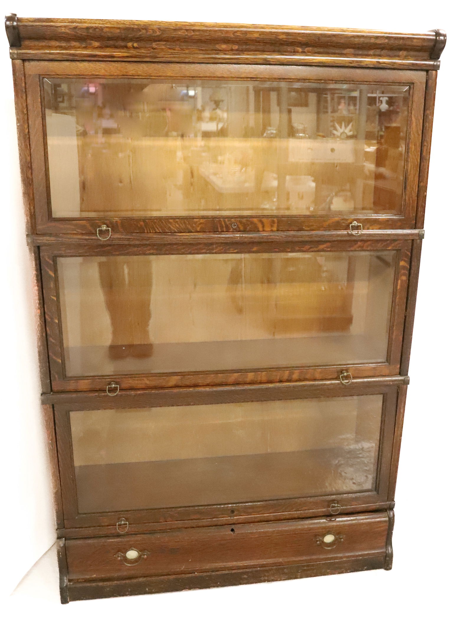 OAK STACK BOOKCASE: THREE SECTION OVER BOTTOM DRAWER. BEVELED GLASS FRONTS. 53" X 34" X 12". PLEASE READ CAREFULLY - SINCE THIS IS A COIN SALE PLEASE NOTE. ITEMS MUST BE PAID FOR THROUGH LIVE AUCTIONEERS OR WITH