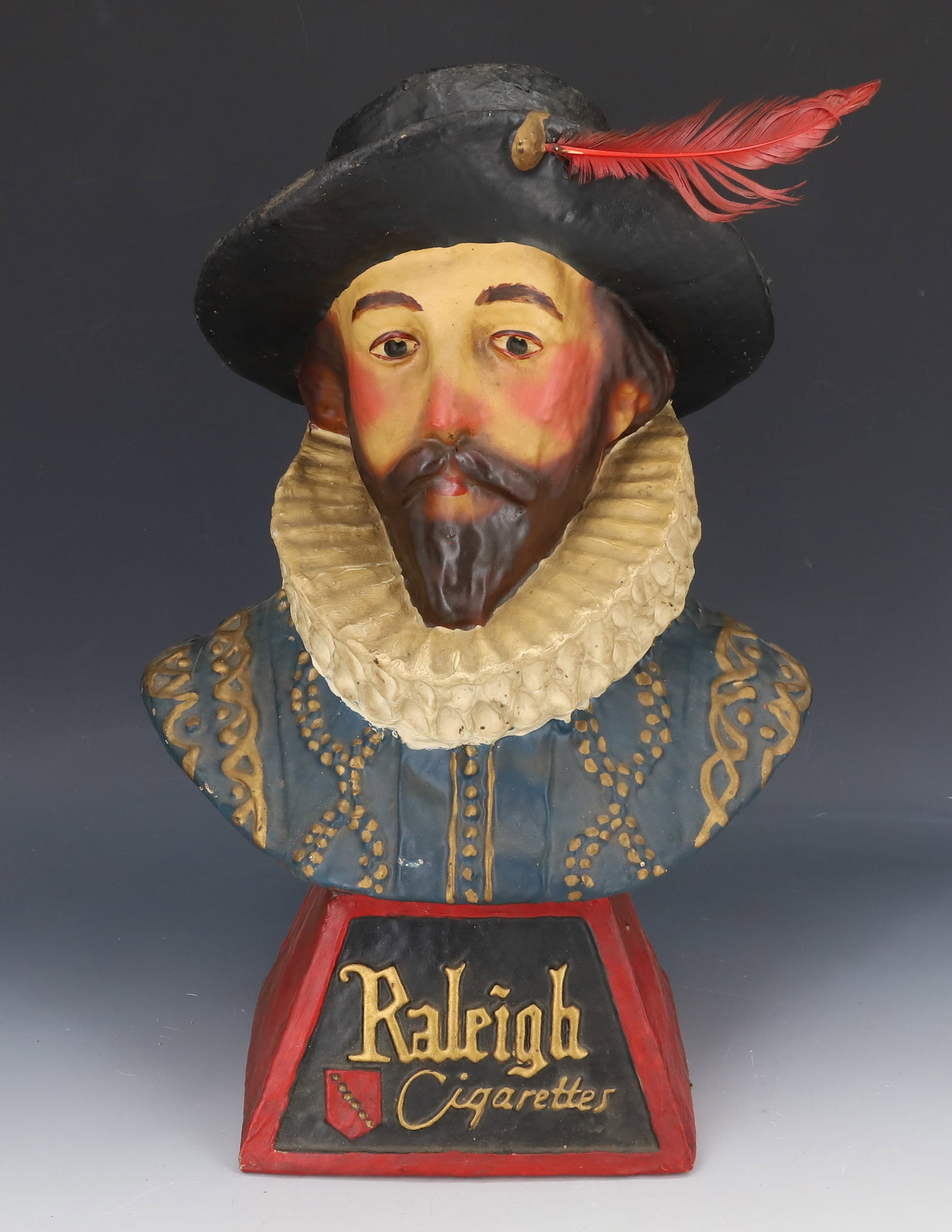PAPIER-MACHE "RALEIGH CIGARETTES" ADVERTISER: PAINTED PRESSED/MOLDED PAPER. MRKD. "RALEIGH CIGARETTES" ON FRONT. LABEL ON INTERIOR "OLD KING COLE, CANTON, OHIO" 14 3/4" H. PLEASE READ CAREFULLY - SINCE THIS IS A COIN SALE PLEASE NOTE. ITEMS MUST