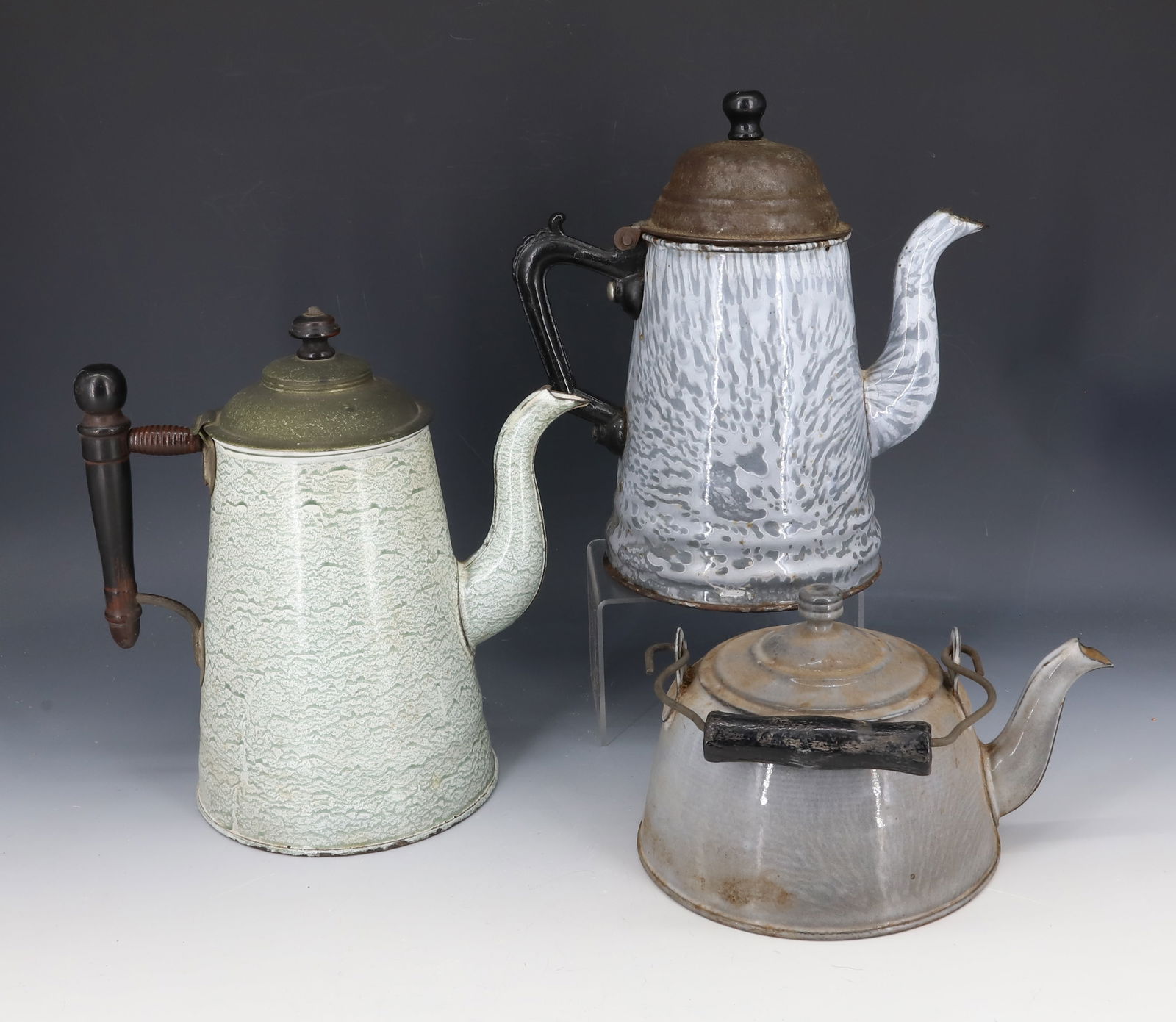 (3) AGATEWARE TEAPOTS: SMALLEST GRAY AGATE IS MRKD. ON BOTTOM "L&G MFG. CO." 7 1/2" WIDE. GRAY SWIRL AGATE IS MRKD. ON BOTTOM "GRANITE IRON WARE, 1877" 9 1/2" H. LIGHT GREEN / WHITE WITH BLACK WOODEN HANDLE AND TIN LID. PLE