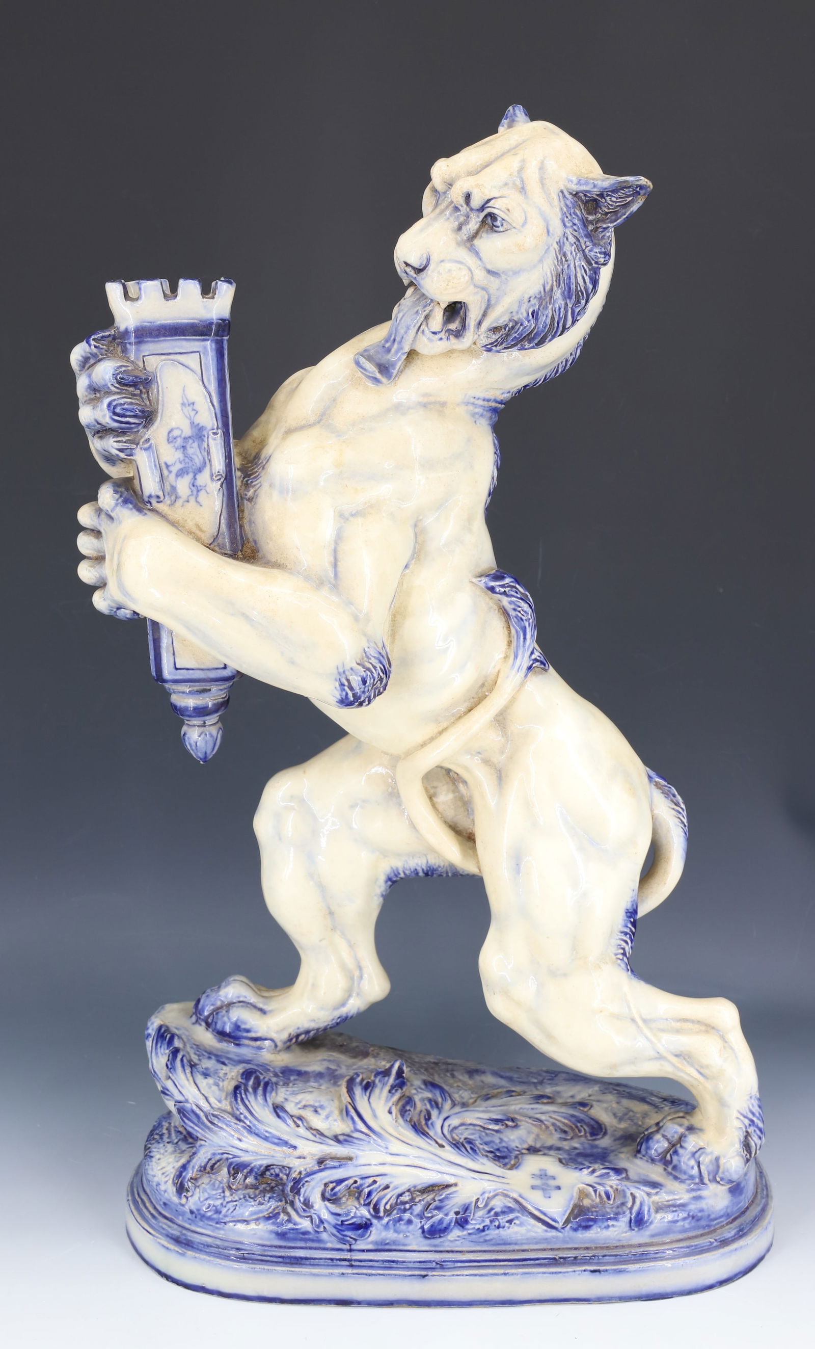 BLUE / WHITE FAIENCE LION CANDLE HOLDER: LION / TIGER STANDING ON OVAL BASE. STYLE OF SAINT-CLEMENT OR GALLE. MRKD. ON BOTTOM. 21" X 13". PLEASE READ CAREFULLY - SINCE THIS IS A COIN SALE PLEASE NOTE. ITEMS MUST BE PAID FOR THROUGH LIVE AUCT