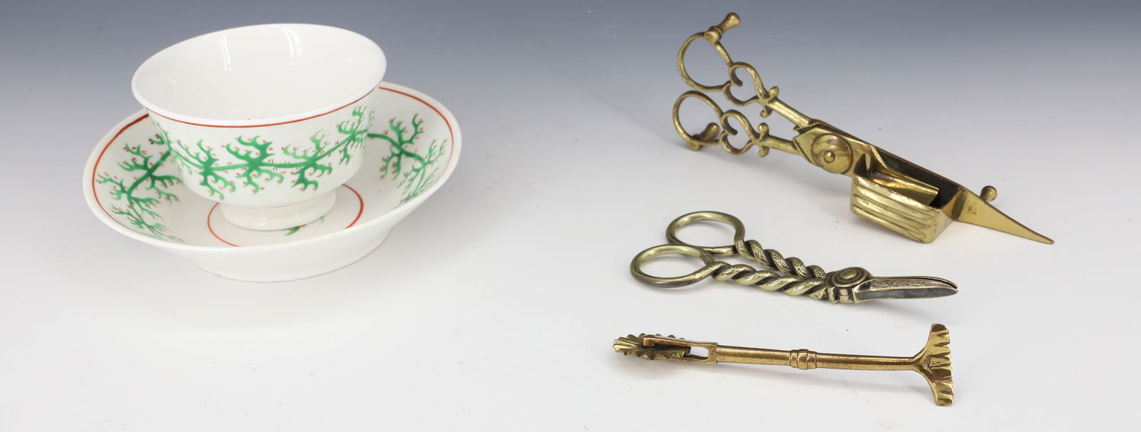 LOT OF BRASS AND HANDLESS CUP / SAUCER: BRASS GRAPE SCISSORS 4 3/4" L., CANDLE SNUFFER AND PIE CRIMPER. WITH, EARLY CUP / SAUCER WITH CORAL PATTERN IN GREEN / RED.