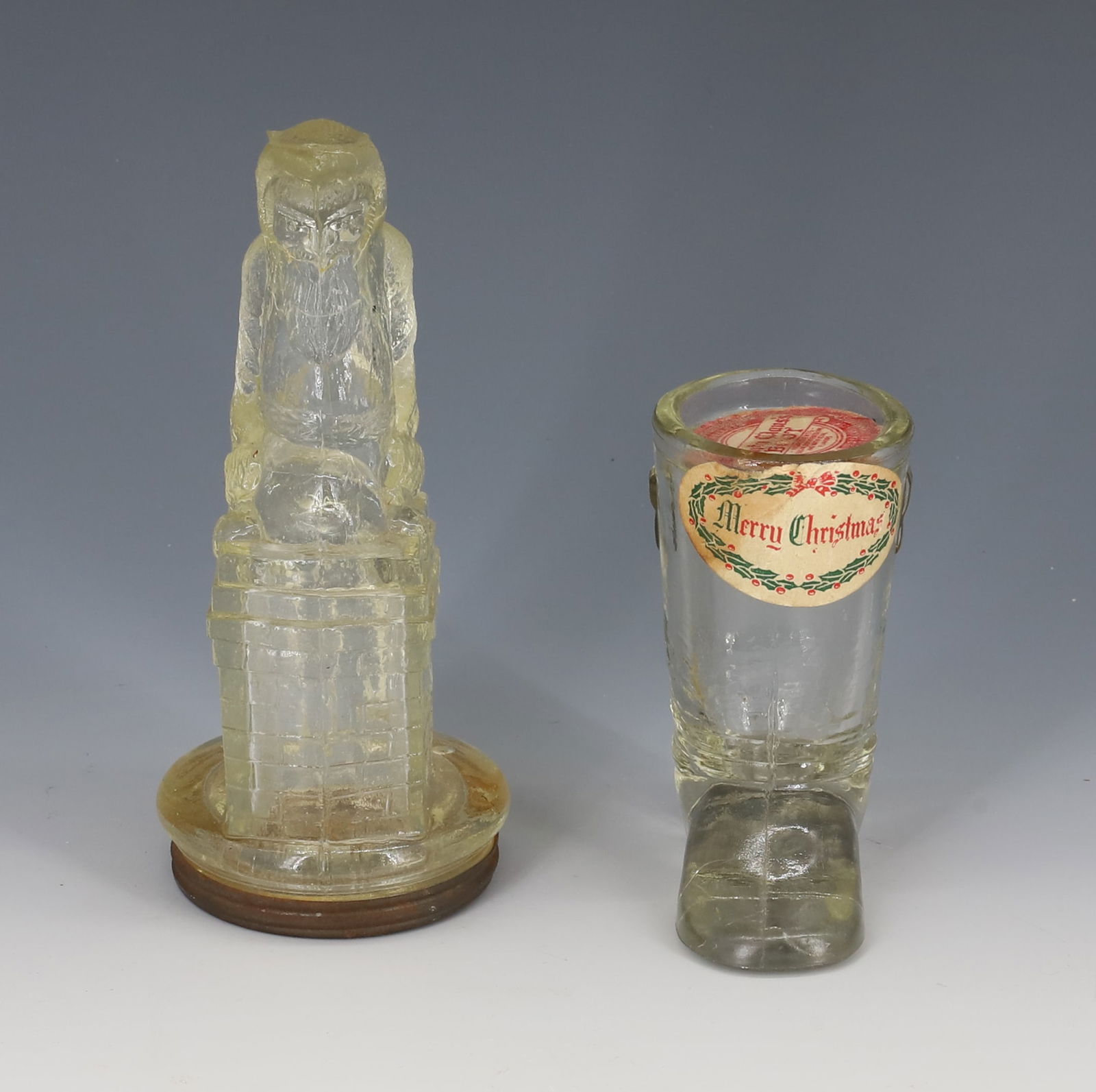 SANTA CLAUS AND BOOT CANDY CONTAINERS: EMBOSSED GLASS. SANTA / BELSNICKLE HAS TIN BOTTOM. 5" H. BOOT HAS "MERRY CHRISTMAS" STICKER AND "SANTA CLAUS'S BOOT" PAPER INSERT.