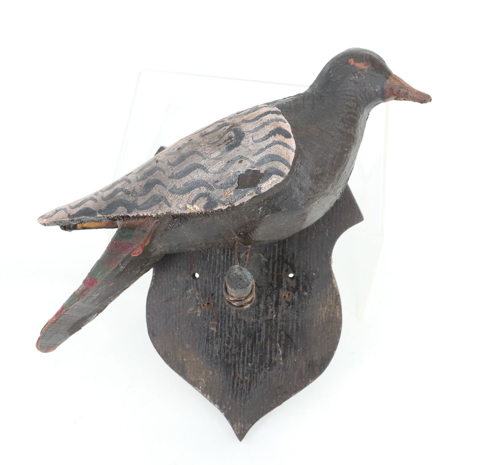 FOLK ART CARVED BIRD: CARVED AND PAINTED. MOUNTED ON PERCH WITH SHAPELY WOODEN PLAQUE. BIRD IS 9 1/2" L.