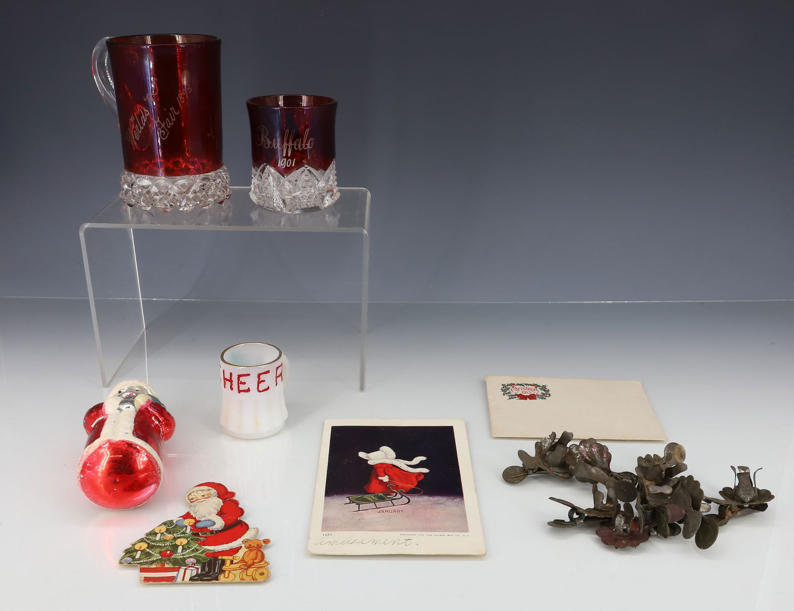 LOT OF CHRISTMAS ITEMS AND RUBY GLASS: MERCURY GLASS SANTA CLAUS WITH TREE 5 1/4". CHRISTMAS 1913 ENVELOPE. JANUARY POSTCARD. (2) RUBY GLASS SOUVENIR CUPS. SMALLER MRKD. "BUFFALO 1901" 2 3/4" H. "WORLD'S FAIR 1893, CLARENCE SMITH". 4 1/4"