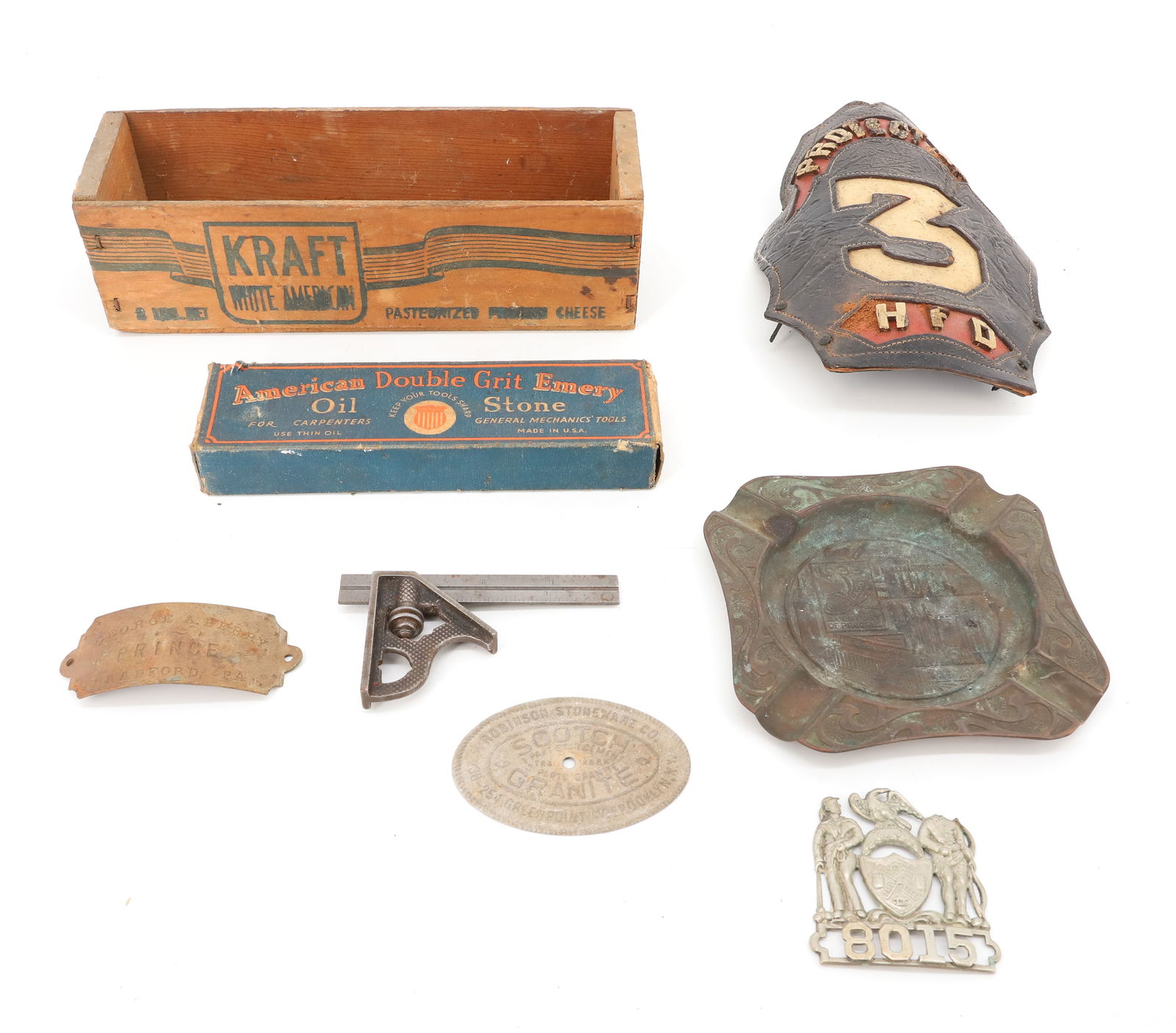 VARIETY OF ANTIQUE SMALLS: INCLUDING: LEATHER FIREMAN'S HELMET SHIELD, METAL NYPD HAT BADGE "8015", 1933 BRASS CHICAGO WORLD'S FAIR ASHTRAY (WORN), CHEESE BOX, EMERY STONE IN BOX AND MORE. PLEASE READ CAREFULLY - TEMS