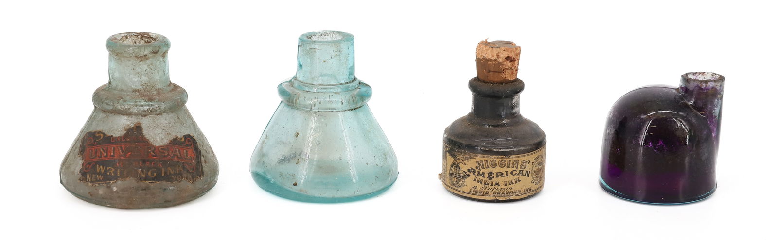 (4) GLASS INKWELLS: AQUA. (2) WITH ORIGINAL LABELS. "UNIVERSAL WRITING INK" AND "HIGGIN'S AMERICAN INDIA INK". TWO WITHOUT LABELS, ONE IS STAND PURPLE FROM INK. LARGEST AQUA MRKD. BIXBY ON BOTTOM 2 7/8" X 2 1/2". 