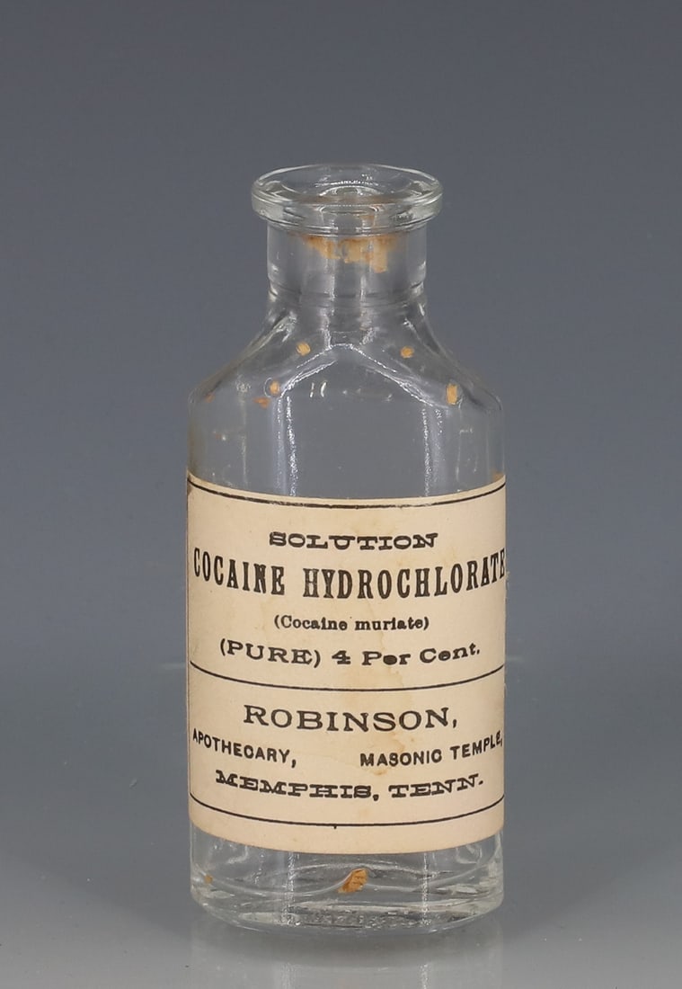 ROBINSON APOTHECARY "COCAINE" BOTTLE: CLEAR GLASS BOTTLE W/ PAPER LABEL. 3 1/2" H. PLEASE READ CAREFULLY - ITEMS MUST BE PAID FOR THROUGH LIVE AUCTIONEERS OR WITH CASH OR CHECK IN PERSON - Terms for Purchasing and Shipping of Auction Item